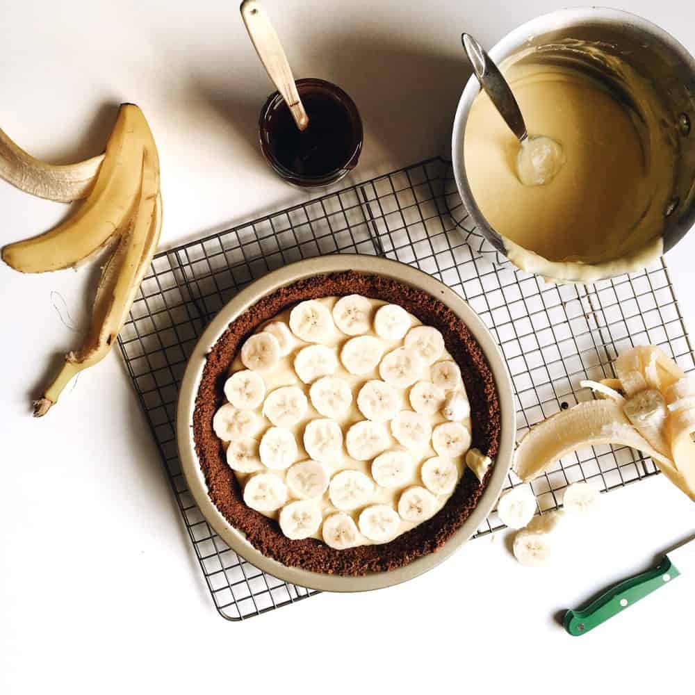 banana cream pie with oatmeal cookie crust recipe by the wood and spoon blog by kate wood. A simple press in crust made up of store bought crunchy crisp oatmeal cookies (i use gmomma's) is filled with a vanilla and banana flavored pastry cream and slices of real bananas. The whole thing is topped with whipped cream and extra banana for garnish. This recipe is a great summer or spring time cream pie recipe and can easily feed a crowd at your next gathering or party. Find the recipe at thewoodandspoon.com