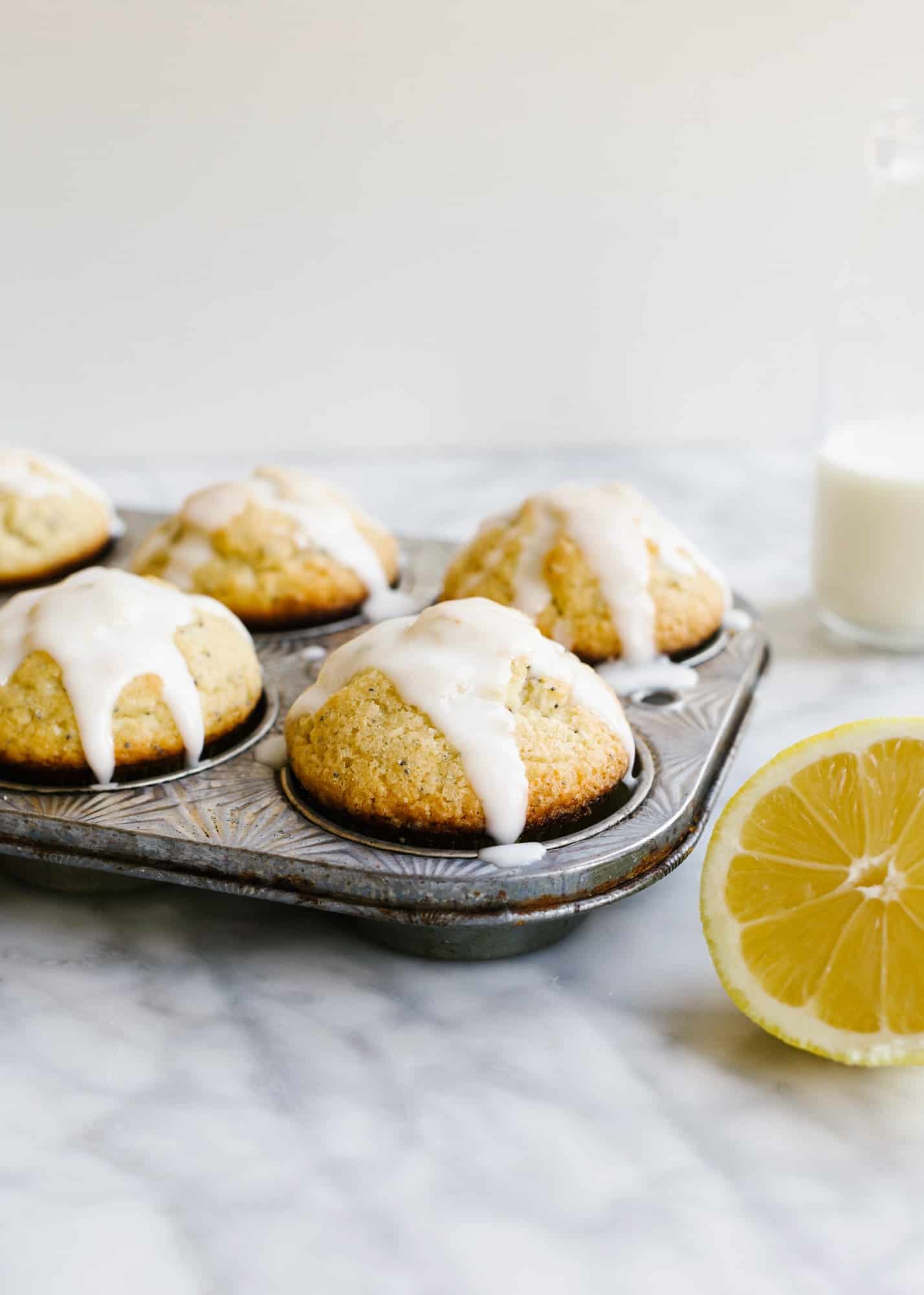 Lemon Poppy Seed Muffins by Wood and Spoon blog. These are light and fluffy homemade butter muffins scented with fresh lemon zest and juice. Poppy seeds throughout add flavor and texture and a simple confectioner's sugar glaze icing on top adds extra sweet and tang. Learn how to make these easy breakfast and brunch treats for a crowd on thewoodandspoon.com