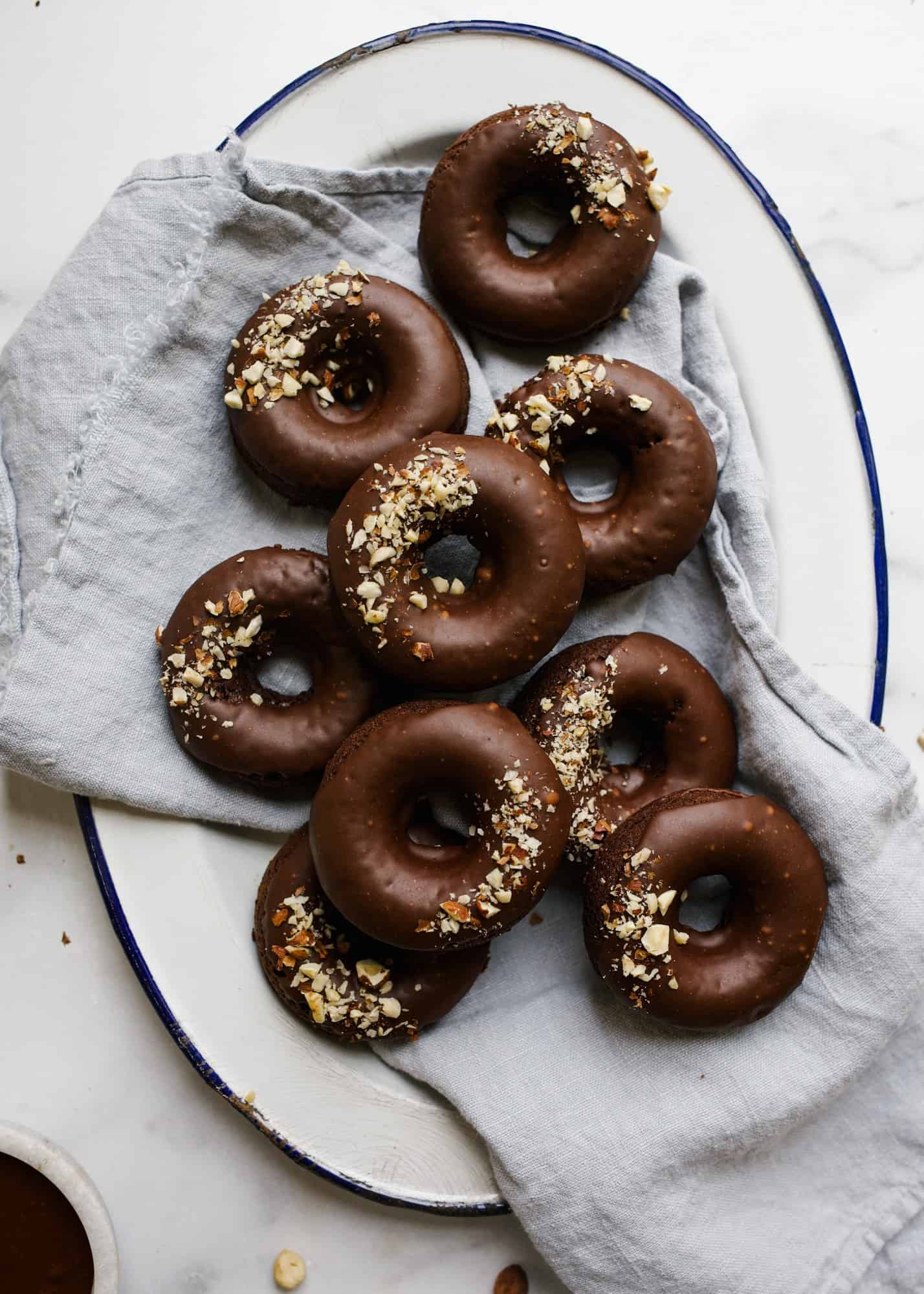 Chocolate Hazelnut Doughnuts by Wood and Spoon blog. These are baked dark chocolate cocoa powder donuts makes with melted butter and topped with a chocolate hazelnut glaze. Sprinkled nuts on top beauty up these quick breakfast pastries that can be made in one bowl! Read more about the recipe on thewoodandspoon.com.