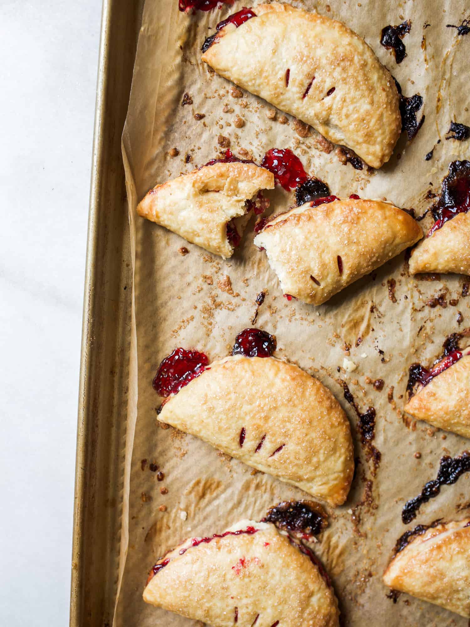 Cherry Lime Hand Pies Recipe by The Wood and Spoon Blog by Kate Wood. This mini hand pies are personal pop tart desserts filled with ripe summer black and red cherries and zesty lime. A great alternative to fried pies, these desserts are sweet, make ahead, and use a buttery, homemade pie crust that gets flaky and delicious. The recipe is simple but learn all about how to make hand pies and homemade pop-tarts here on thewoodandspoon.com