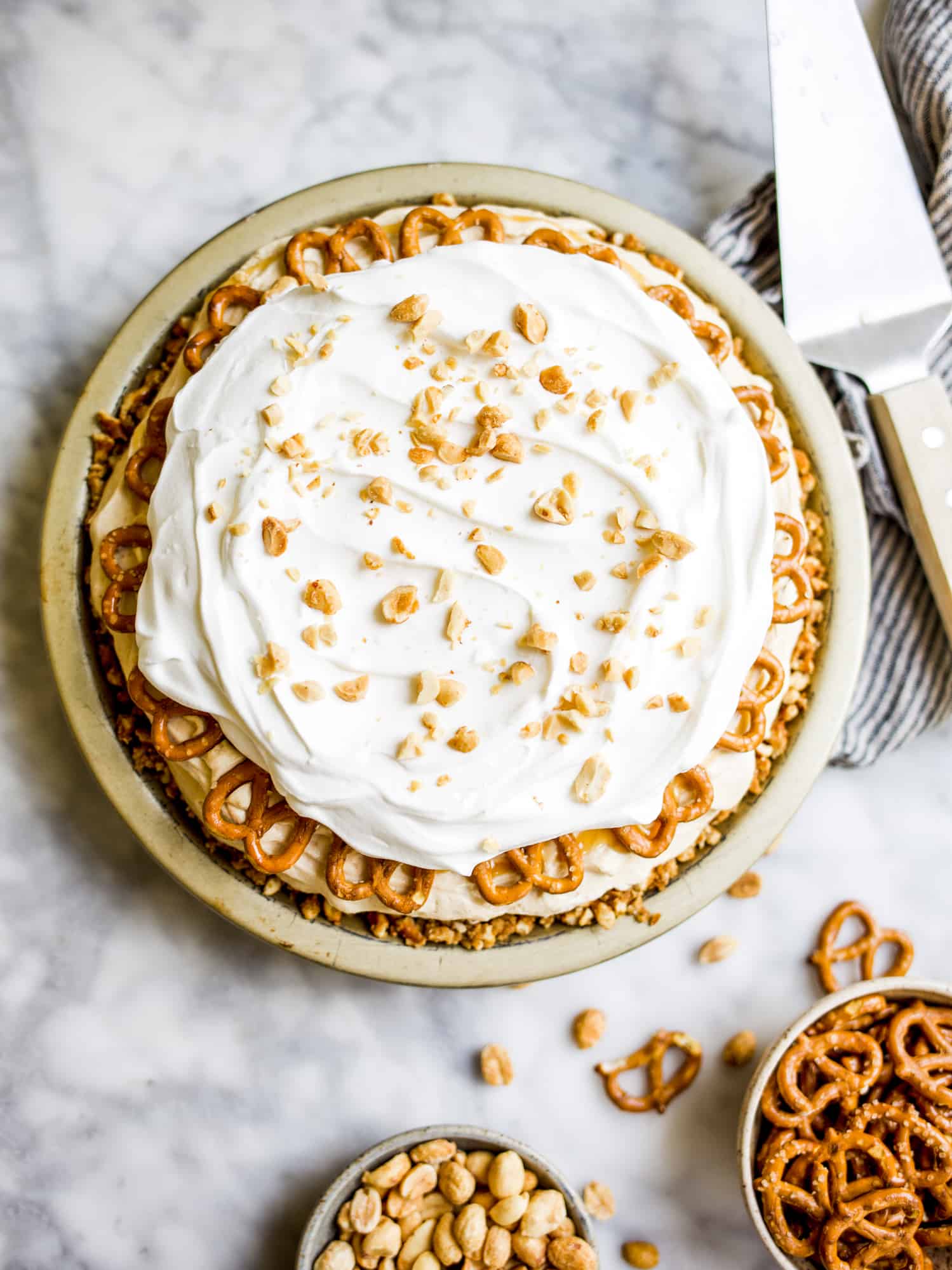 Peanut Butter Pie Recipe By The Wood and Spoon Blog. This is a simple make ahead dessert recipe inspired by Paula Deen's Mrs. Salter's pie. This is a cream cream cheese and whipped cream peanut butter filling topped with salted salty caramel and chopped peanuts. The whole thing is stuffed in a brown sugar, butter, and pretzel pie crust. This recipe takes less than 30 minutes and is a great treat to make for a dinner party or casual gathering. Find the recipe at thewoodandspoon.com