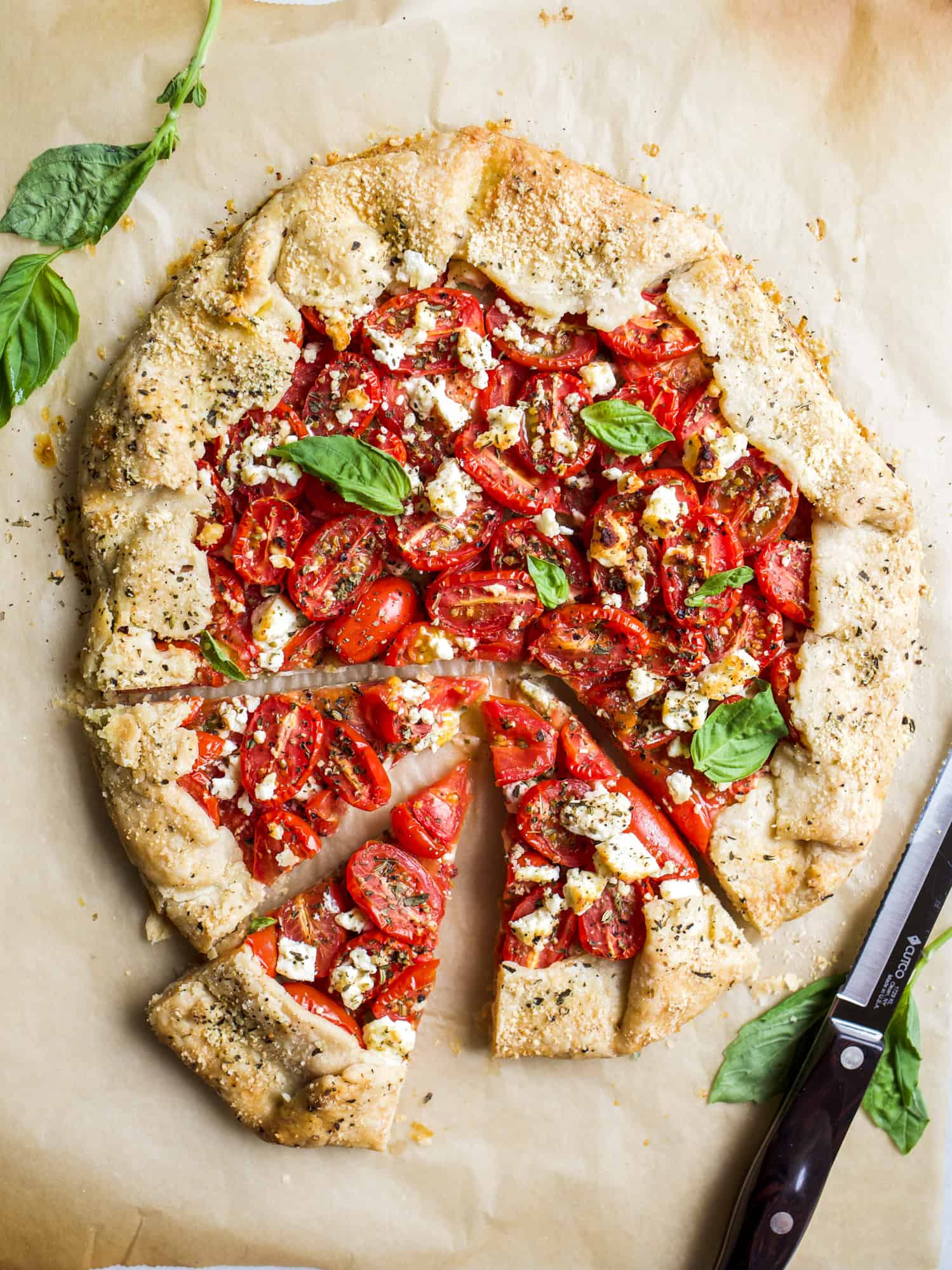 Tomato Galette with Pesto and Feta By The Wood and Spoon Blog by Kate Wood. This is a simply, flaky butter pie crust filled with ripe heirloom or Roma tomatoes, basil, pesto, and feta cheese. The whole thing is baked as a rustic galette style tart and is topped with parmesan cheese. This is a delicious way to use summer cherry tomatoes and a simple way to use pie crust. Find the recipe for this fun vegetable dinner or appetizer on thewoodandspoon.com