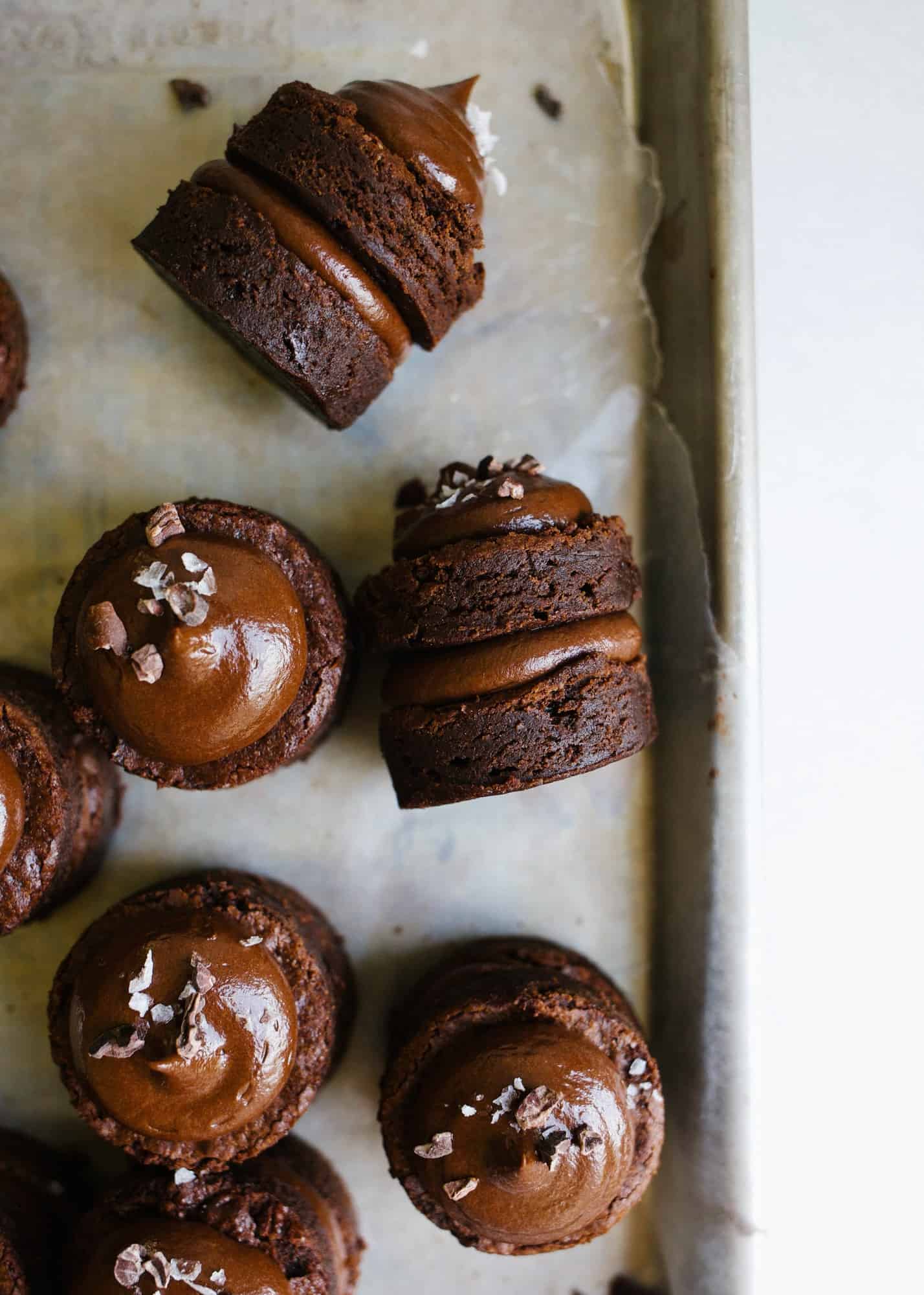 Brownie Petit Fours by Wood and Spoon blog. These are tiny bite sized brownies filled with a rich salted chocolate ganache filling. You can prepare these two ways: either stacked in fancy tiered dessert form or in a single bite of ganache coated brownie. Read more about how to make ganache and these fancy treats on thewoodandspoon.com by Kate Wood holiday entertaining cocktail desserts