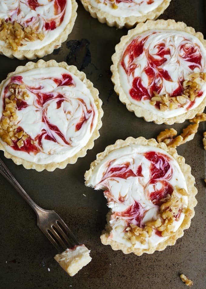 White Chocolate Cheesecake Tartlets with Blood Orange Swirl by Wood and Spoon Blog by Kate Wood. These are almost shortbread tart crusts filled with a no bake cream cheese and white chocolate filling. The quick blood orange jam here adds a swirl or flavor and tang. You can substitute in another favorite jam here! These come together quickly and make for a nice make-ahead dessert option for small dinner parties. They are an easy to make simple fancy dessert for the spring! If you're wondering how to use blood oranges, this is how! Read more on thewoodandspoon.com