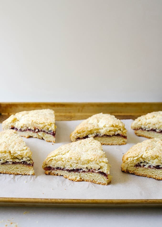 Jam-Filled Scones by Wood and Spoon Blog. These are tender and rich cake scones, perfect for morning breakfast or brunch. This recipe makes buttery brown edges and is soft from the cream. The scones are stuffed with jelly of choice and topping with sugar. Find the recipe for the tea party favorite on thewoodandspoon.com