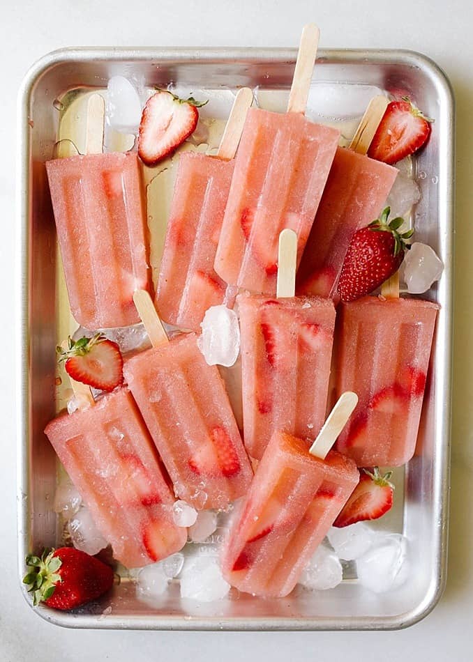 Rose Popsicles by Wood and Spoon blog. These boozy frose pops are made with rose wine and a puree of pears and strawberries. Just a few simple ingredients make this summer water dessert something that will be perfect for pool and outdoor BBQ parties all season. Find these lightened up snacks on thewoodandspoon.com