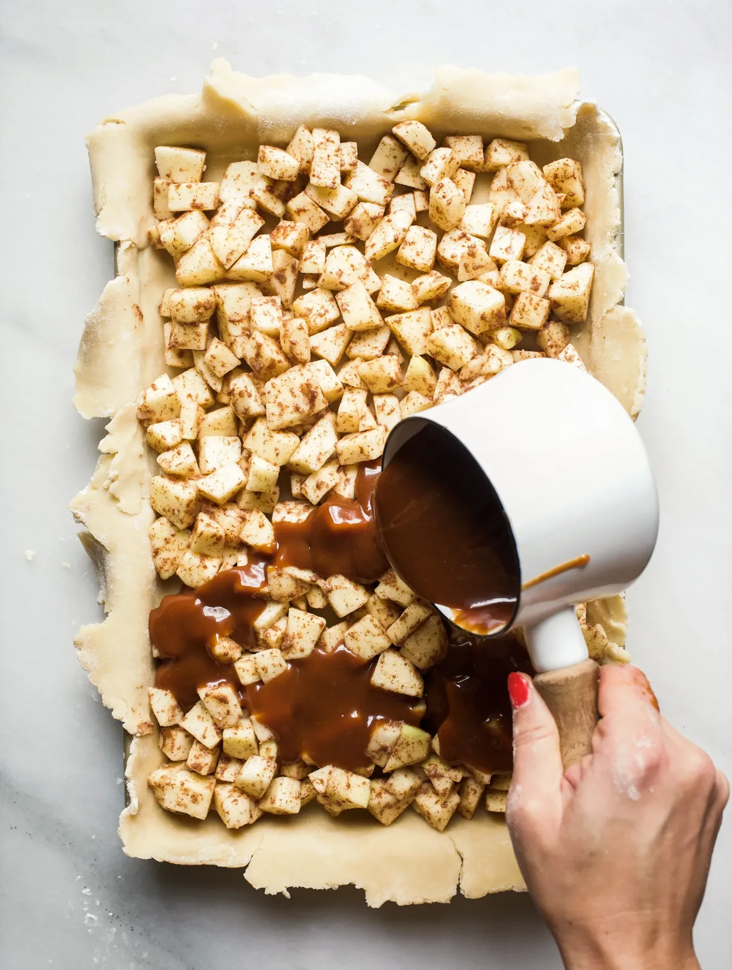 Caramel Apple Slab Pie Recipe by The Wood and Spoon Blog by Kate Wood. This is a pie recipe prepared in a jelly roll pan, quarter sheet pan, or a 9"x 13" pan. Filled with tart autumn apples and a salted caramel sauce inspired by bobby flay, fall dessert is perfect for serving a crowd and can easily be made ahead. Find the details and how to make your own Thanksgiving inspired treat on thewoodandspoon.com