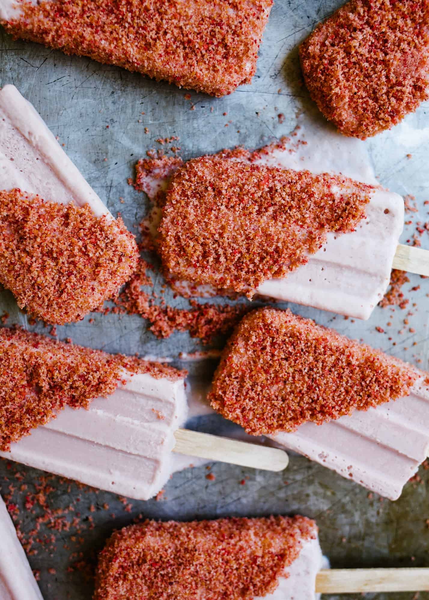 Strawberry Shortcake Popsicles by Wood and Spoon blog. These frozen treats were inspired by the classic novelty treats. A creamy fresh strawberry popsicle is made in a blender and dipped in a freeze-dried strawberry and vanilla cookie butter crumble. The end product is a refreshing and yummy dessert perfect for these summer days. Learn how simple the recipe is on thewoodandspoon.com .