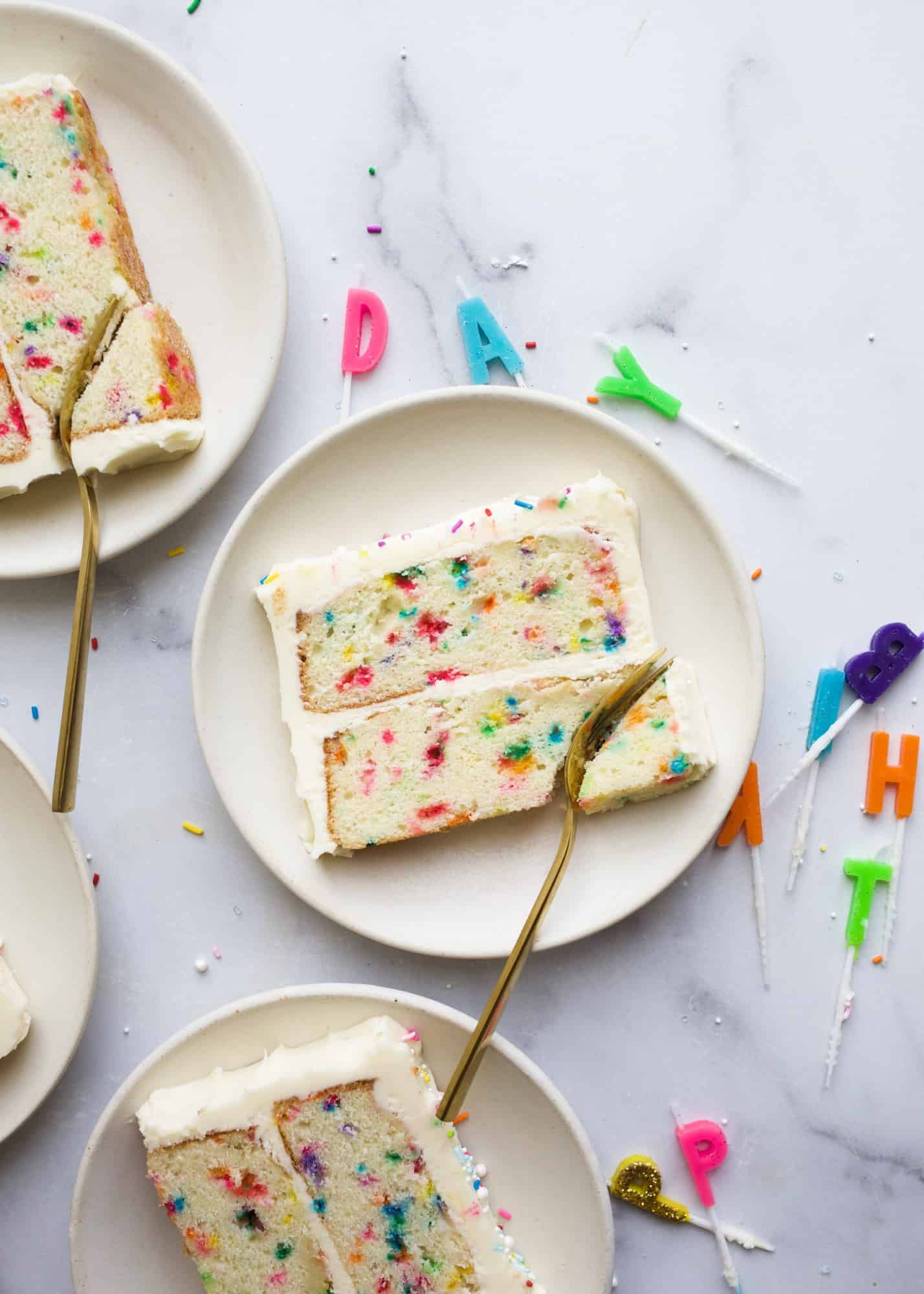 Funfetti Cake by wood and Spoon blog. This is a sprinkle birthday cake that tastes like the boxed cake mix! Features a clear vanilla extract American buttercream made with cream cheese and loaded of colorful rainbow sprinkles. Learn how to make this cake at home with real ingredients for celebrations and kids birthdays on thewoodandspoon.com