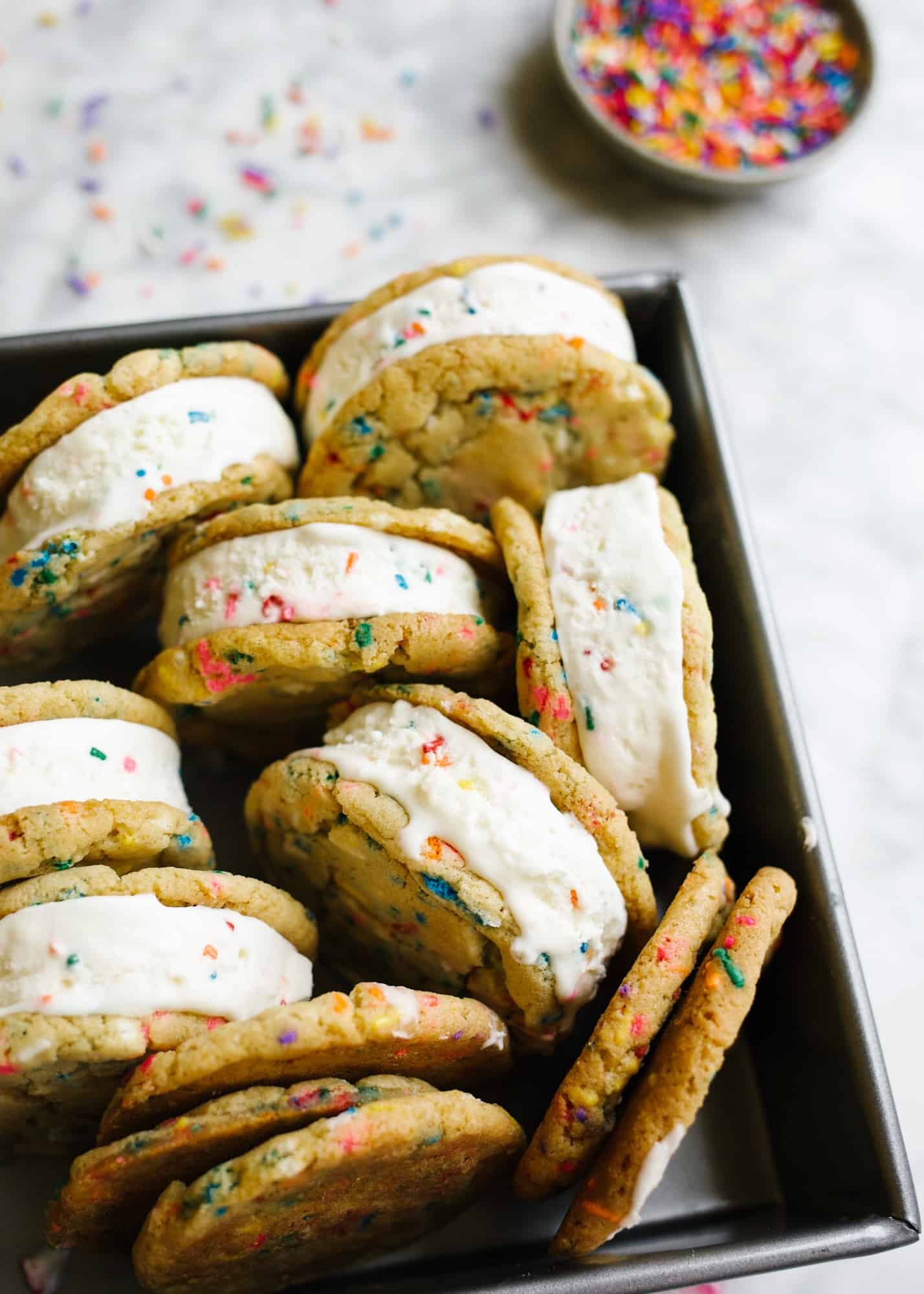 Funfetti Ice Cream Sandwiches by Wood and Spoon blog. These are soft and chewy sugar cookies loaded with sprinkles and box cake mix flavor. These nostalgic treats are stuffed with a no-churn ice birthday cake ice cream and make terrific summertime treats. Learn how simple these frozen desserts are on thewoodandspoon.com