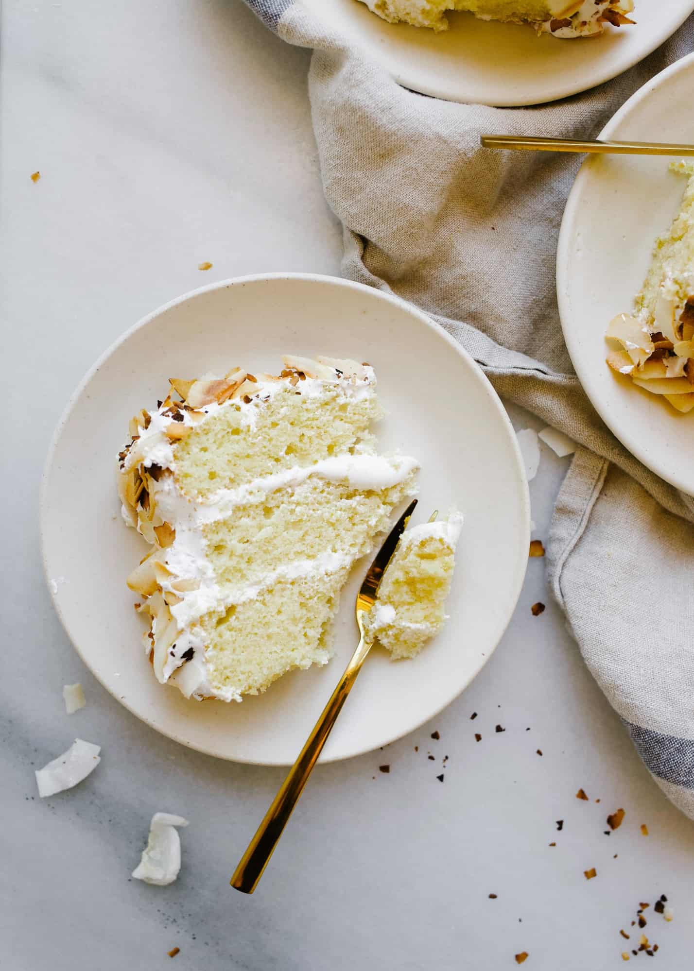 Coconut Key Lime Cake by Wood and Spoon. This is a lime zest scented fluffy butter cake with a coconut marshmallow 7 minute egg white frosting and coated in toasted flaked coconut. This cake tastes like summer but is great for spring parties and gatherings. Serve this to a crowd or try out a cream cheese coconut frosting instead! Find the recipe and learn how to make this 3 tiered layer cake on thewoodandspoon.com