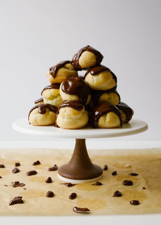 Tiramisu Cream Puffs by Wood and Spoon blog. This is a recipe for homemade pate chow filled with a coffee whipped cream and topped with a thick chocolate ganache glaze. The pastry is made simply on the stove and baked into round profiteroles. The cream is made with Kahlua flavored liquor and mascarpone cheese. The topping is rich with dark chocolate and heavy cream. Learn how to make these fancy finger food desserts on thewoodandspoon.com by Kate Wood.