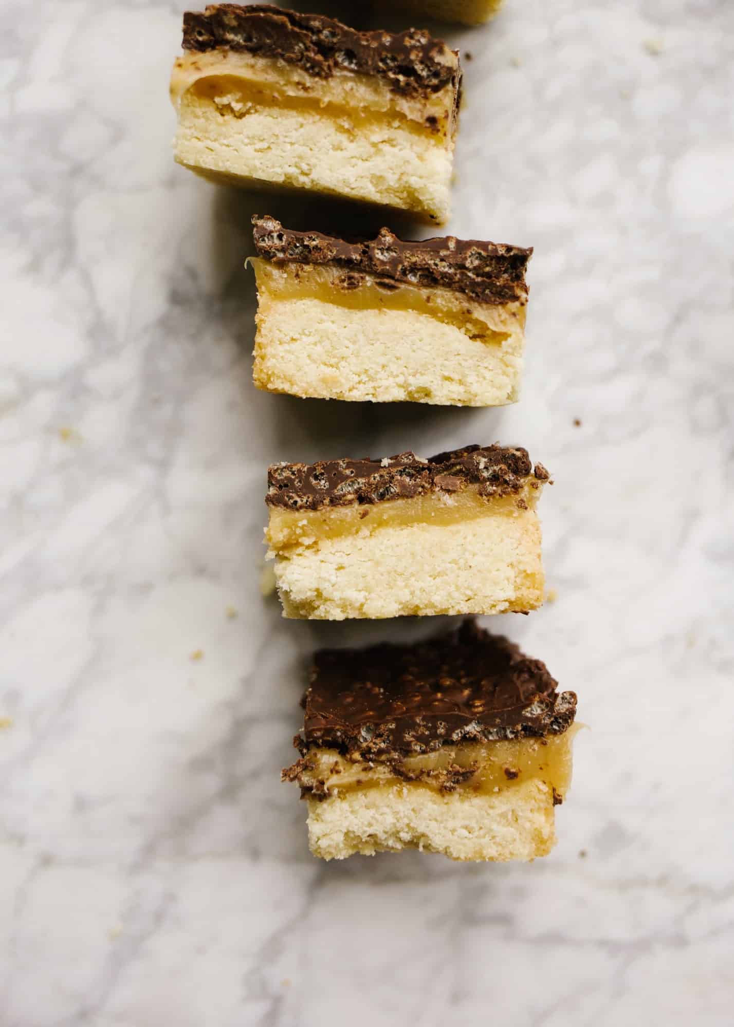 Crispy Millionaire Bars by Wood and Spoon. These are shortbread millionaire bars with a caramel center and chocolate and rice Krispy topping. The bars are gooey, buttery, and crisp thanks to the topping. This is a great make-ahead dessert and can serve a crowd! Great for casual get togethers too! Find the recipe and how to on thewoodandspoon.com