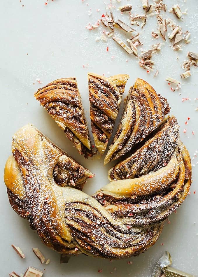 Peppermint Bark Bread Recipe by Kate Wood of The Wood and Spoon blog. This is a sweet yeast bread similar to babka filled with a semisweet chocolate filling and bits of chopped white chocolate peppermint bark. The bread is swirled and braided into a wreath and baked in a cast iron skillet. This bread is festive enough for dessert but able to be eaten as breakfast too. Find the tutorial for how to braid bread and a review of the wolf gourmet counter oven on thewoodandspoon.com Christmas holiday recipe!