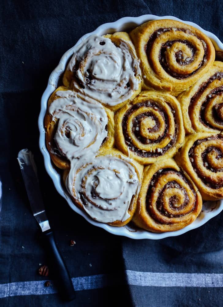 Sweet Potato Cinnamon Rolls Recipe by The Wood and Spoon Blog by kate Wood. These are fluffy, light cinnamon rolls and that make several pans or just a few large oversized big cinnamon rolls. These contain sweet potato puree or you can use pumpkin puree from a can. Filled with a cinnamon and brown sugar pecan filling and topped with a simple and easy cream cheese frosting / icing / glaze. Make these ahead if desired. Find the recipe for these fall favorite best breakfast buns at thewoodandspoon.com