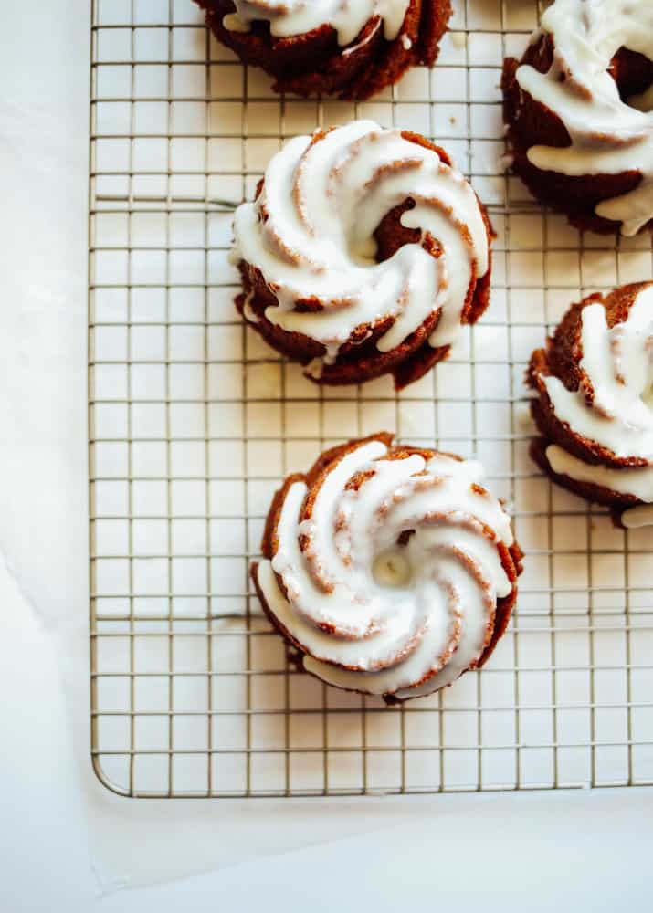 Ginger Molasses Bundt Cakes Recipe by The Wood and Spoon Blog by Kate Wood. Simple, one bowl recipe of flavorful and warmly scented cakes sweetened with molasses and spices including cinnamon and ginger. There is a simple white chocolate frosting glaze icing on top. you can modify these mini bundt cakes to be larger bundt cakes or even use a loaf pan, a round cake pan, or a square baking dish. Find the recipe and other fall / winter/ holiday recipes on thewoodandspoon.com