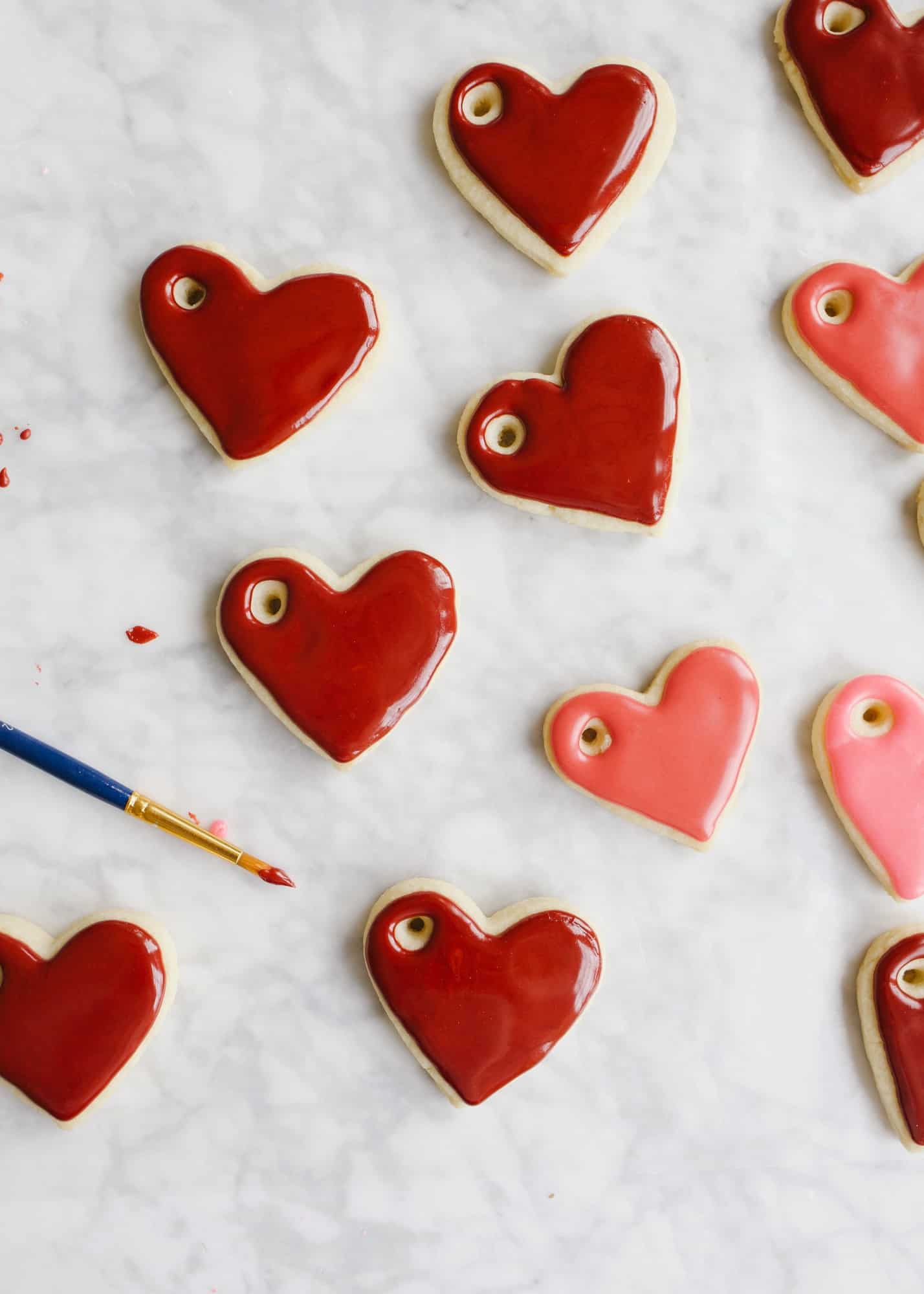 Sugar Cookie Gift Tags by Wood and Spoon blog. Use this tutorial to create, mini frosted iced heart sugar cookies to use as garland, napkin ring holders, gift tags, name tags, necklaces, and more. This simple tutorial gives you the DIY recipe for hard set cookies with homemade icing and ideas for how to use them for Valentine's Day parties, kid crafts, and more. Read about the recipe and how to on thewoodandspoon.com by Kate Wood