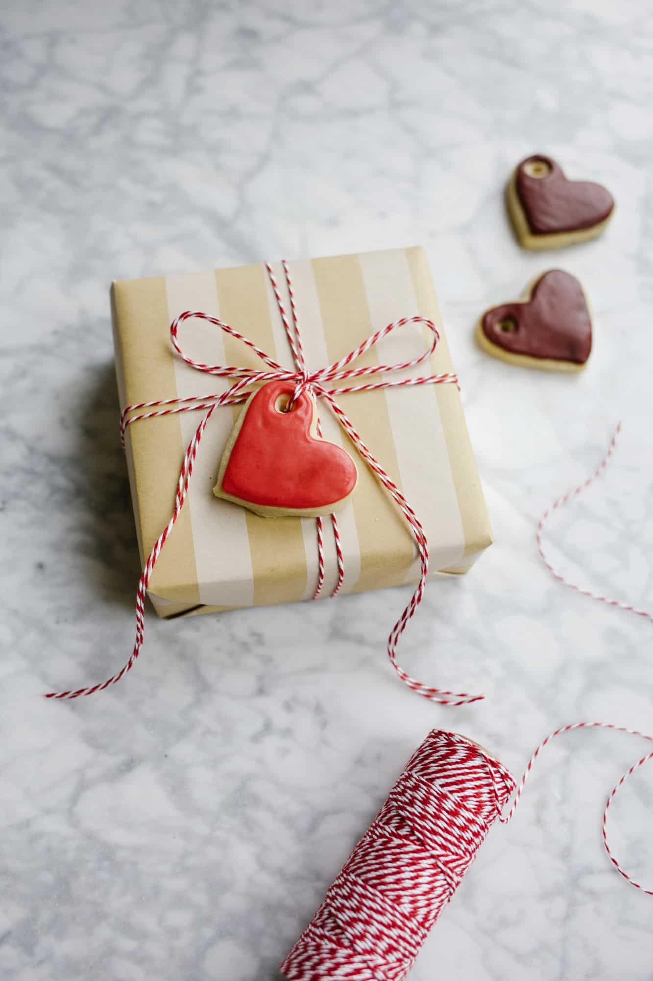 Sugar Cookie Gift Tags by Wood and Spoon blog. Use this tutorial to create, mini frosted iced heart sugar cookies to use as garland, napkin ring holders, gift tags, name tags, necklaces, and more. This simple tutorial gives you the DIY recipe for hard set cookies with homemade icing and ideas for how to use them for Valentine's Day parties, kid crafts, and more. Read about the recipe and how to on thewoodandspoon.com by Kate Wood