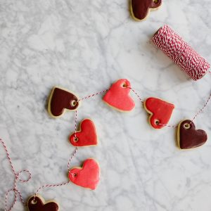 Sugar Cookie Gift Tags by Wood and Spoon blog. Use this tutorial to create, mini frosted iced heart sugar cookies to use as garland, napkin ring holders, gift tags, name tags, necklaces, and more. This simple tutorial gives you the DIY recipe for hard set cookies with homemade icing and ideas for how to use them for Valentine's Day parties, kid crafts, and more. Read about the recipe and how to on thewoodandspoon.com by Kate Wood