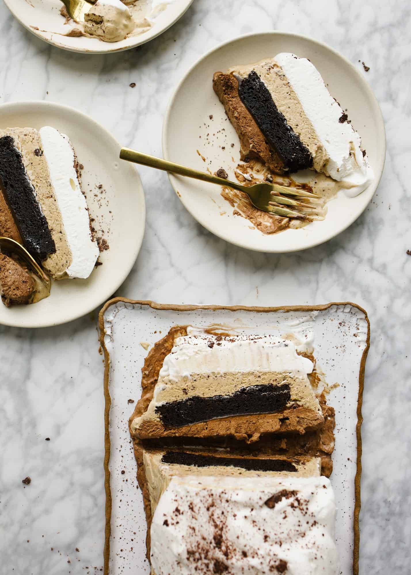 Mocha Brownie Ice Cream Cake by Wood and Spoon. This is a no churn ice cream cake with a slab of box brownie, espresso ice cream, and chocolate frozen dessert. The whole thing is topped with whipped cream and can be garnished with chocolate cookie crumbs, cacao nibs or caramel! Find the how to on this make ahead freezer dessert on thewoodandspoon.com