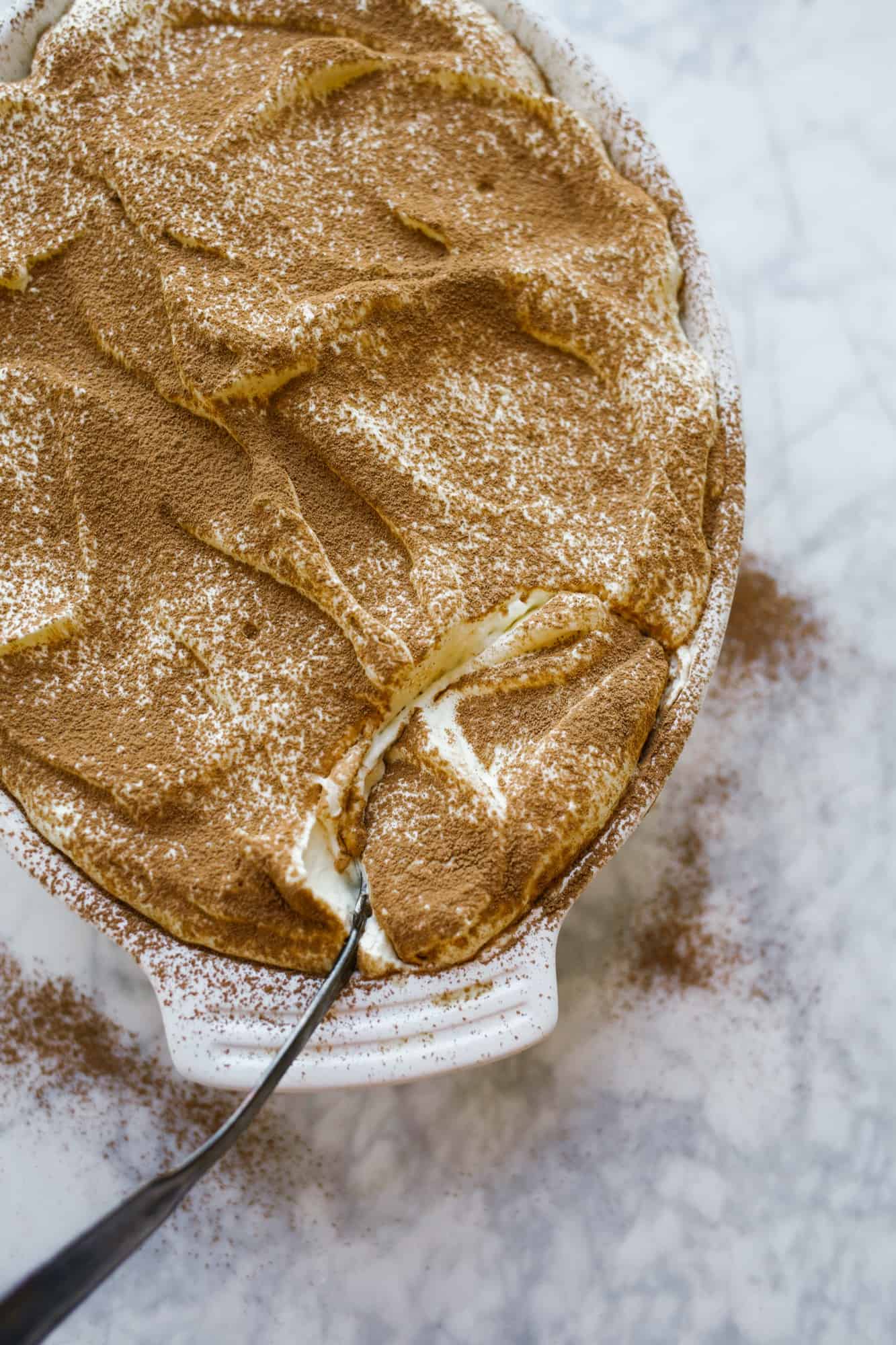 Classic Tiramisu by Wood and Spoon. This Italian dessert is made up of Kahlua and coffee soaked store bought lady fingers, a fluffy whipped cream and mascarpone filling, and cocoa powder. This dessert serves a crowd, is make ahead, and a romantic offering for fancy group dinners. Learn how to make i from scratch on thewoodandspoon.com