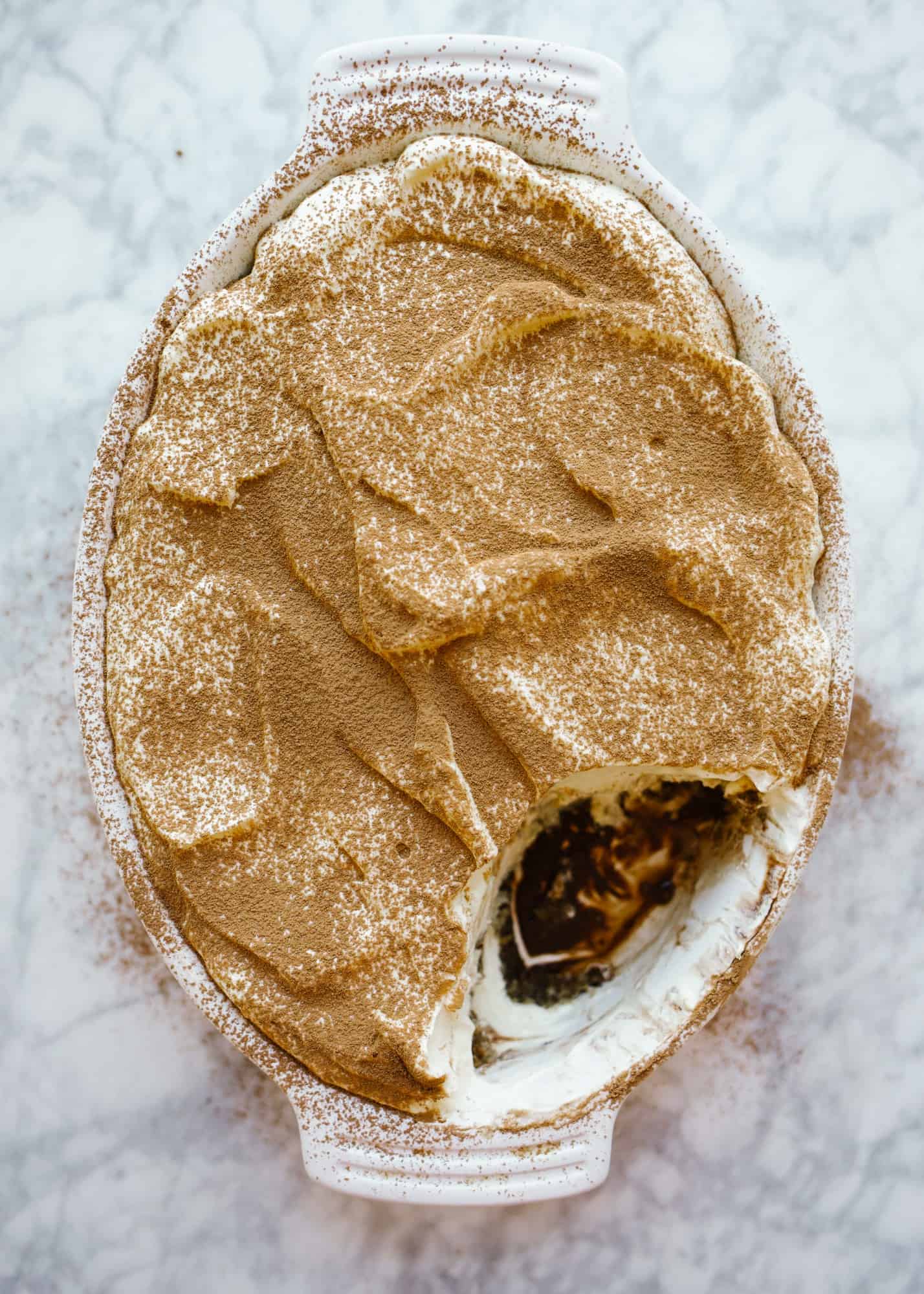 Classic Tiramisu by Wood and Spoon. This Italian dessert is made up of Kahlua and coffee soaked store bought lady fingers, a fluffy whipped cream and mascarpone filling, and cocoa powder. This dessert serves a crowd, is make ahead, and a romantic offering for fancy group dinners. Learn how to make i from scratch on thewoodandspoon.com