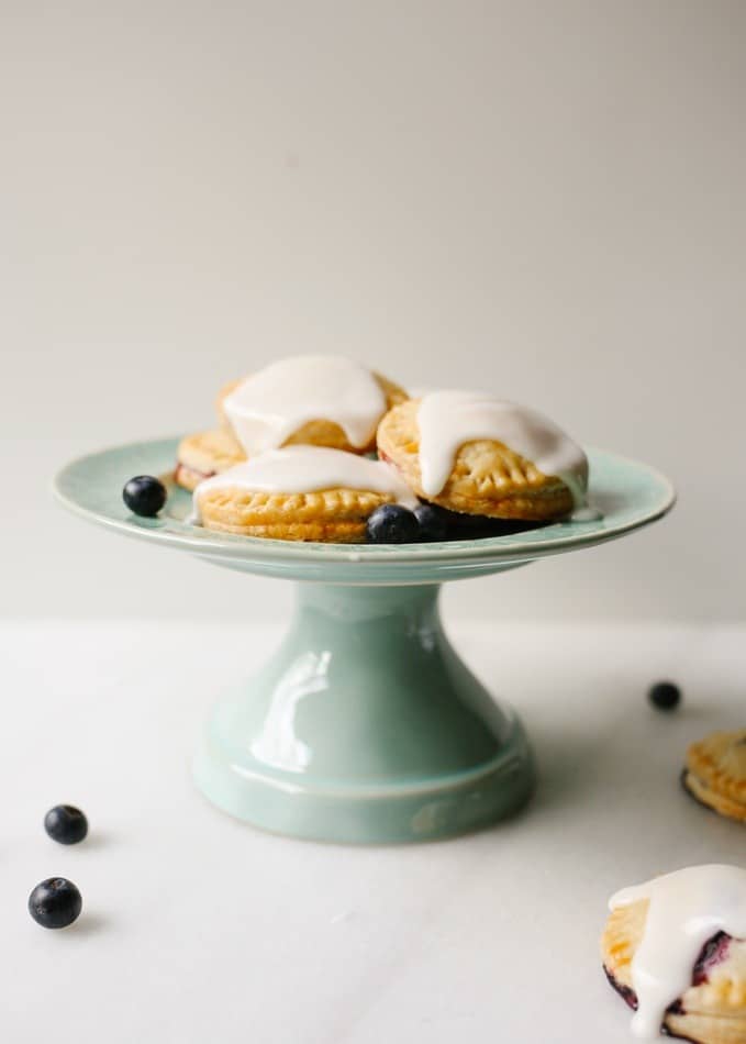 Blueberry Lemon Pop-tarts by Wood and Spoon blog. These are simple hand pies filled with lemon zest, fresh blueberries, and sugar. They're topped with a sweet and tart glaze and a a bit of sugar. The homemade pie dough is flaky and easy to assemble for personal handheld desserts. Find the recipe and learn more about this end of summer treat on thewoodandspoon.com by Kate Wood