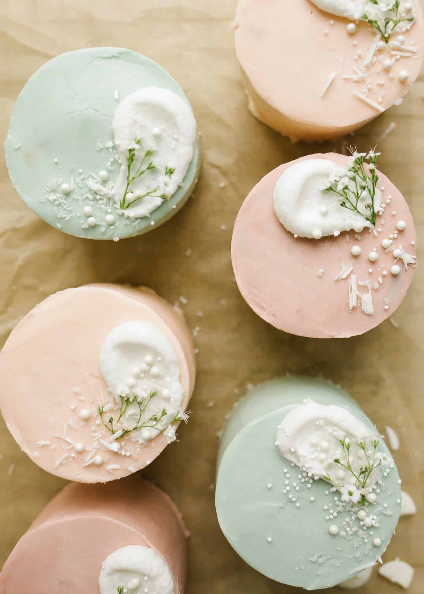 Mini Layer Cakes by Wood and Spoon blog. These are tiny three layer pastel cakes perfect for parties, spring holidays, and Mother's Day. The small vanilla cakes are baked in a sheet pan and then frosted together with a simple American buttercream. The cakes are colored in pale easter colors and served as individual desserts. Perfect mini cake for two. Find the recipe and how to on thewoodandspoon.com by Kate Wood