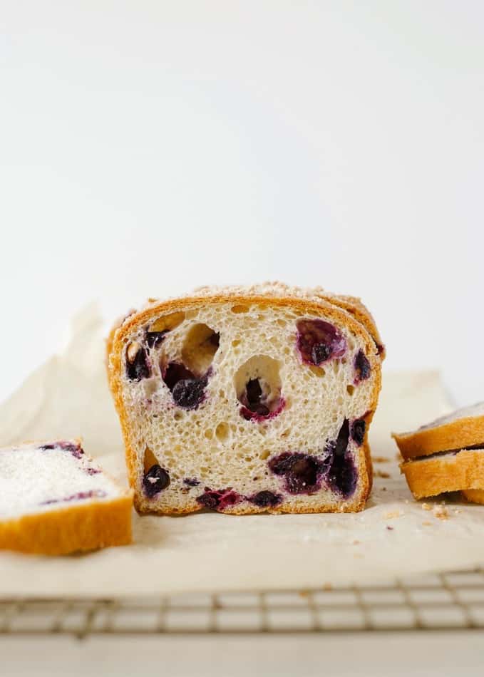 Blueberry Brioche recipe by Wood and Spoon blog. This is a recipe for two yeast loaves of brioche made with butter, egg, and a smidge of sugar. The fluffy white bread is studded with blueberries and seasoned with cinnamon. Each loaf has an optional crumble topping for extra sweet and salty in each bite. Learn how to fold and create this beautiful homemade breakfast treat here at thewoodandspoon.com by Kate Wood.