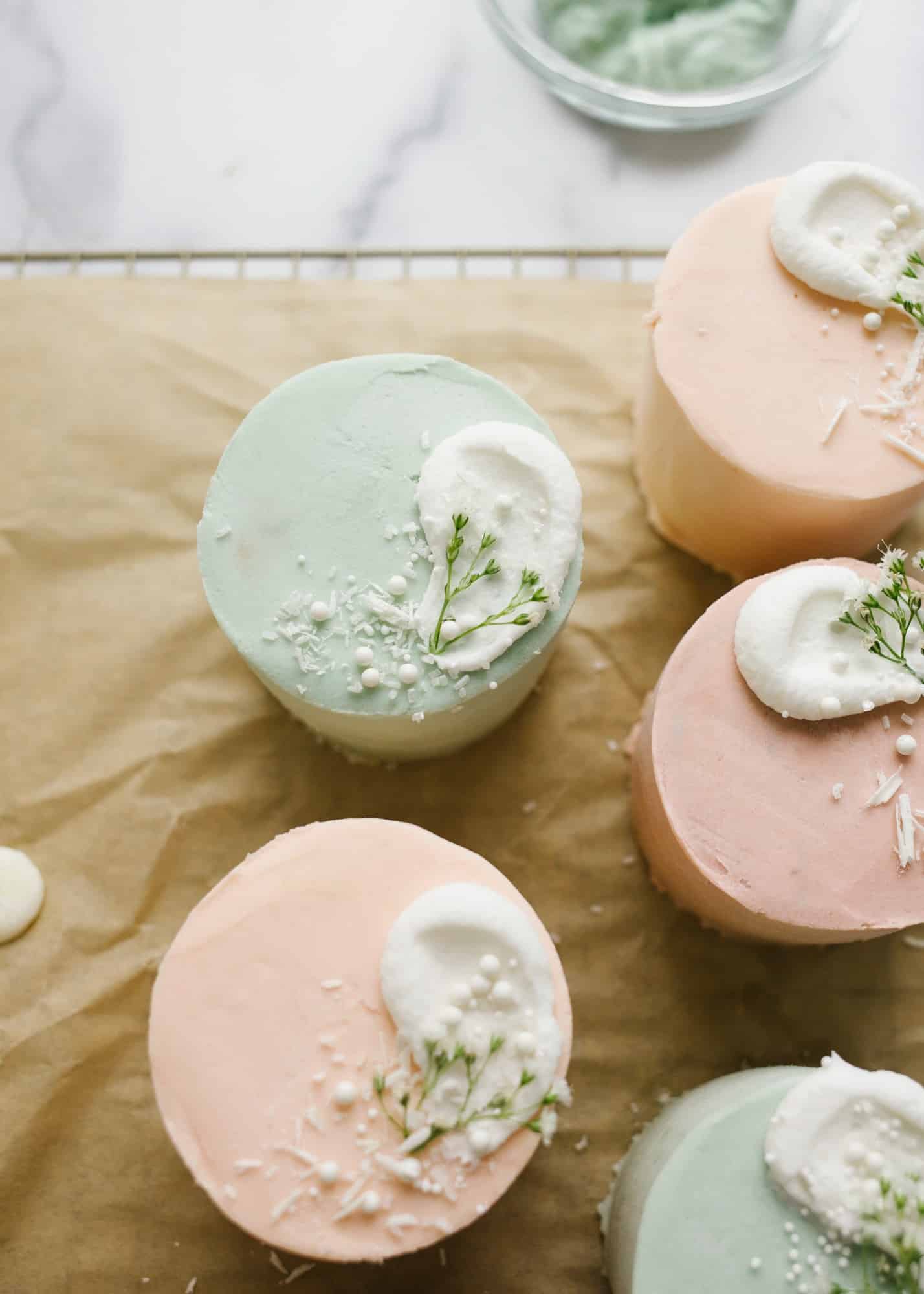 Mini Layer Cakes by Wood and Spoon blog. These are tiny three layer pastel cakes perfect for parties, spring holidays, and Mother's Day. The small vanilla cakes are baked in a sheet pan and then frosted together with a simple American buttercream. The cakes are colored in pale easter colors and served as individual desserts. Perfect mini cake for two. Find the recipe and how to on thewoodandspoon.com by Kate Wood