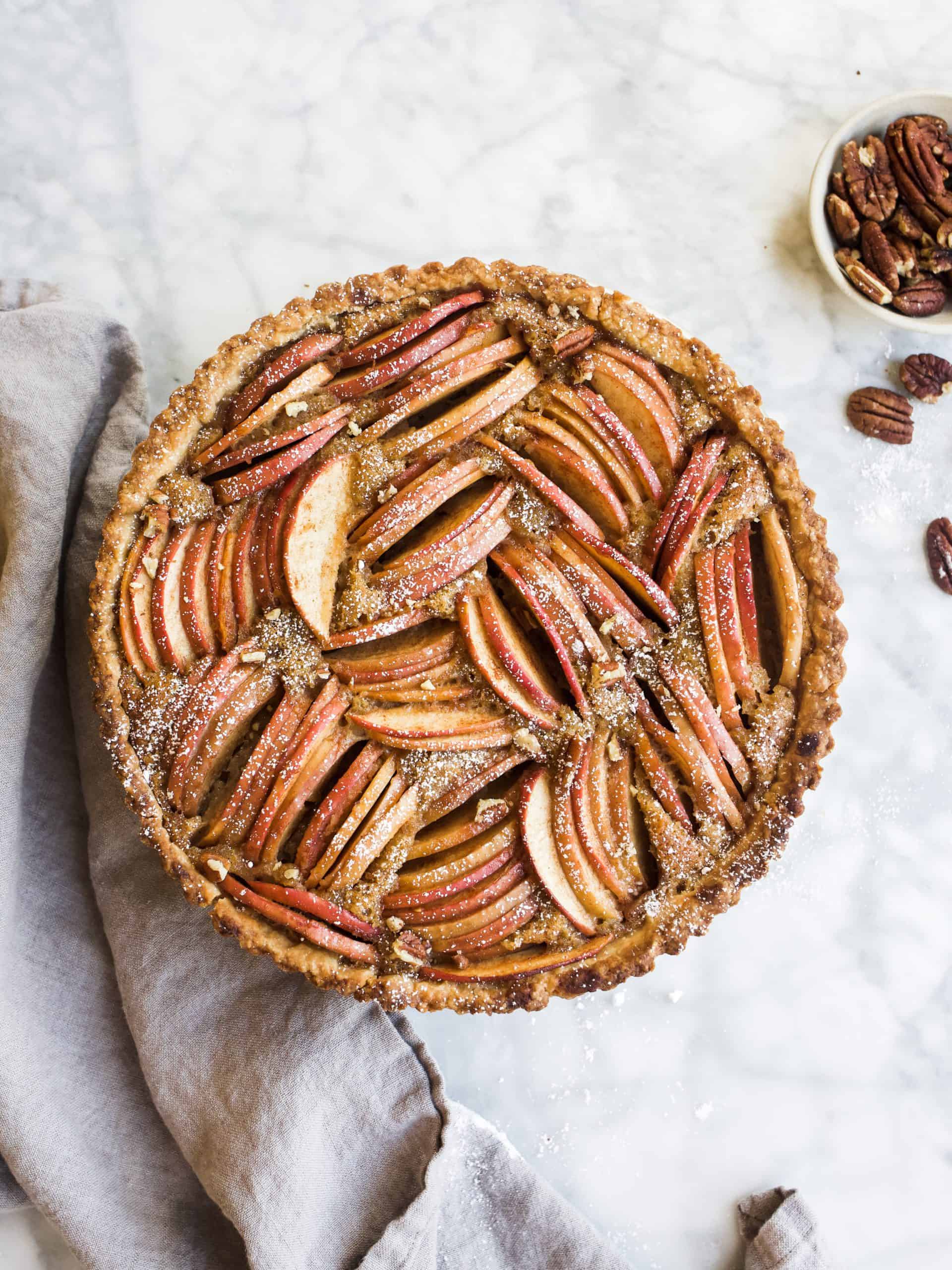 Brown Butter Apple Tart by Wood and Spoon Blog. This is a French apple tart made with a pastry crust, a brown butter filling, and sliced apples on top. The tart is spiced with cinnamon and makes a great alternative for apple pie. To learn how to make this beautiful holiday fruit tart, visit thewoodandspoon.com for the recipe!