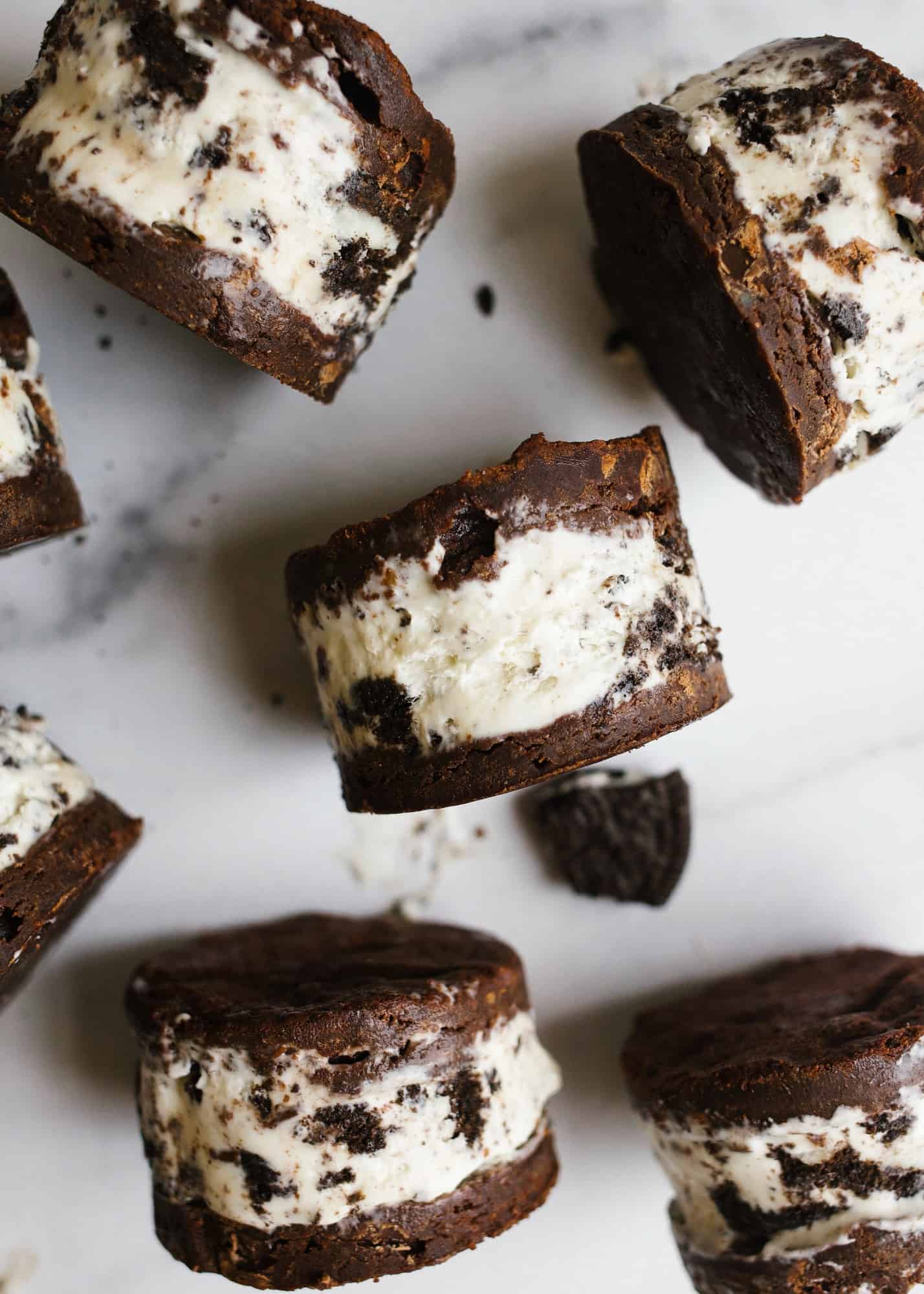 Brownie Ice Cream Sandwiches by Wood and Spoon blog. These are soft baked brownies stuffed with a no churn cookies and cream Oreo ice cream filling. The brownies stay chewy when frozen and this recipe makes a batch to feed a crew. Learn how to make homemade frozen treats without an ice cream maker on thewoodandspoon.com