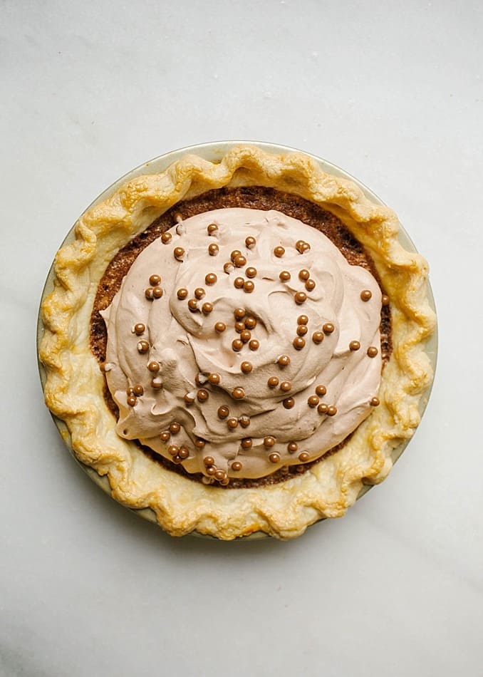 Chocolate Chess Pie by The Wood and Spoon Bly by Kate Wood. This gooey fudge pie is a take on the classic Southern recipe. Make with a flaky pie crust and a cocoa powder fudgy filling, this pie is topped with chocolate whipped cream and chocolate curls. Definitely the prettiest pie you'll see this holiday season. Make this pie for Christmas or Thanksgiving as it serves a crowd and is great for sharing. Find the recipe and other old South recipes on thewoodandspoon.com