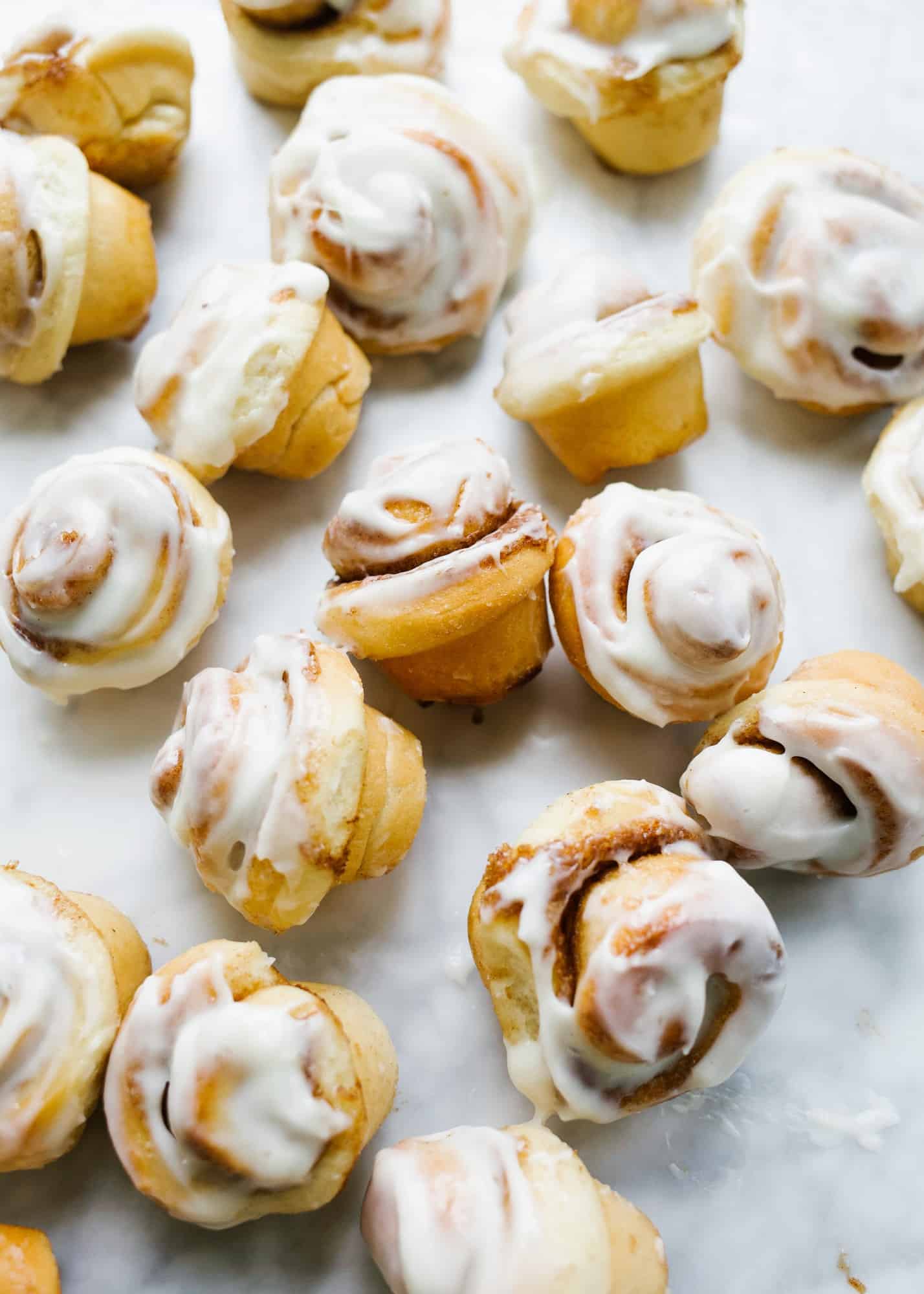 Mini Cinnamon Rolls by Wood and Spoon blog. These are two bite cini minis with a cream cheese frosting or simple sugar glaze. You can fill these with brown sugar and cinnamon or a chocolate Nutella filling. These come together with yeast and butter in a mini cupcake pan and can be made ahead for brunch or breakfast parties. Find the recipe and how to make and roll homemade cinnamon buns on thewoodandspoon.com