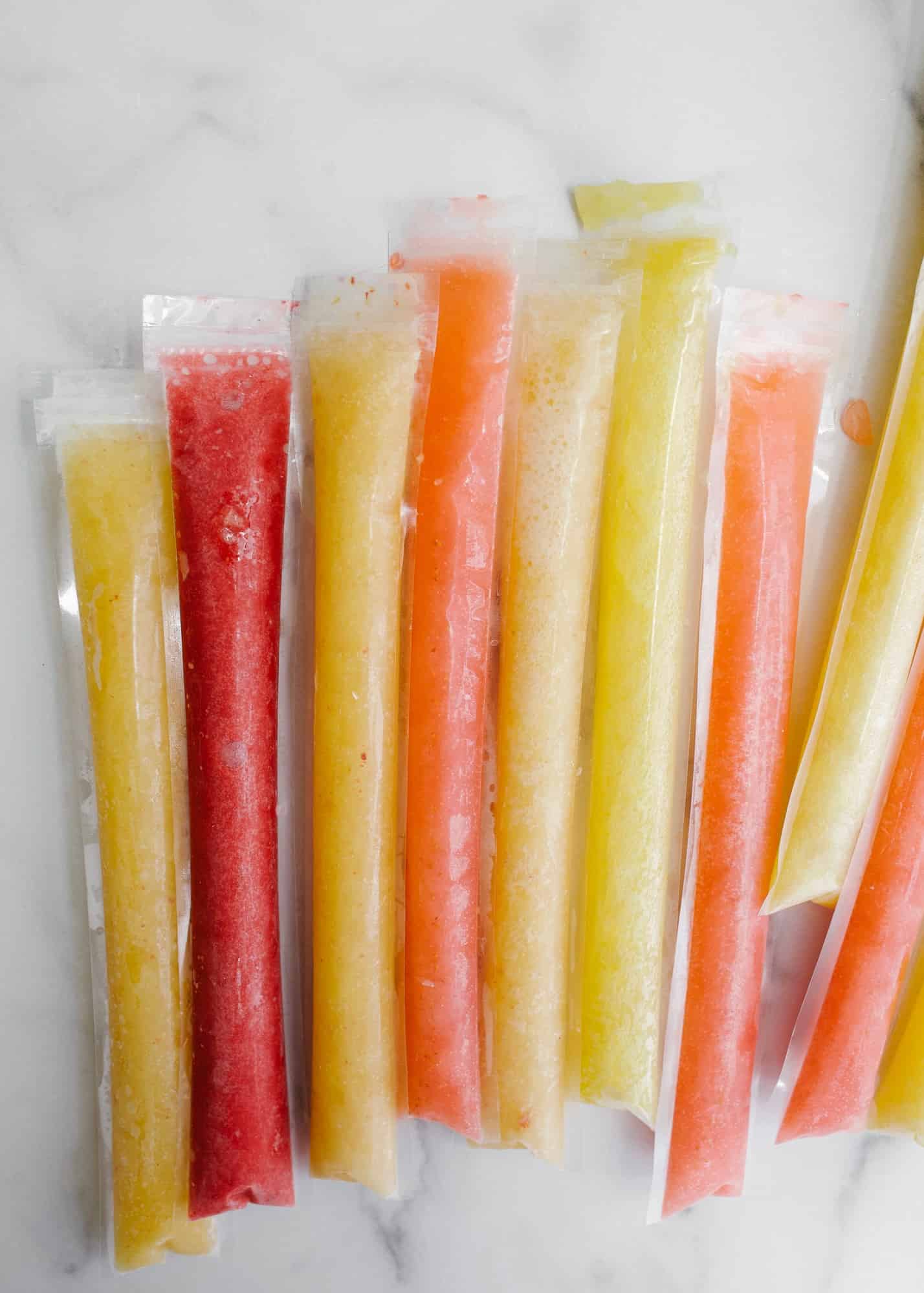 Champagne Cocktail Popsicles by Wood and Spoon. Learn to make homemade mimosa push pops, Bellini popsicles, and strawberry lime champagne frozen treats! These are made in plastic sleeves with fresh real strawberries, peaches, and orange juice and sparkling wine. Find the recipe and learn how to make these boozy summertime frozen desserts on thewoodandspoon.com