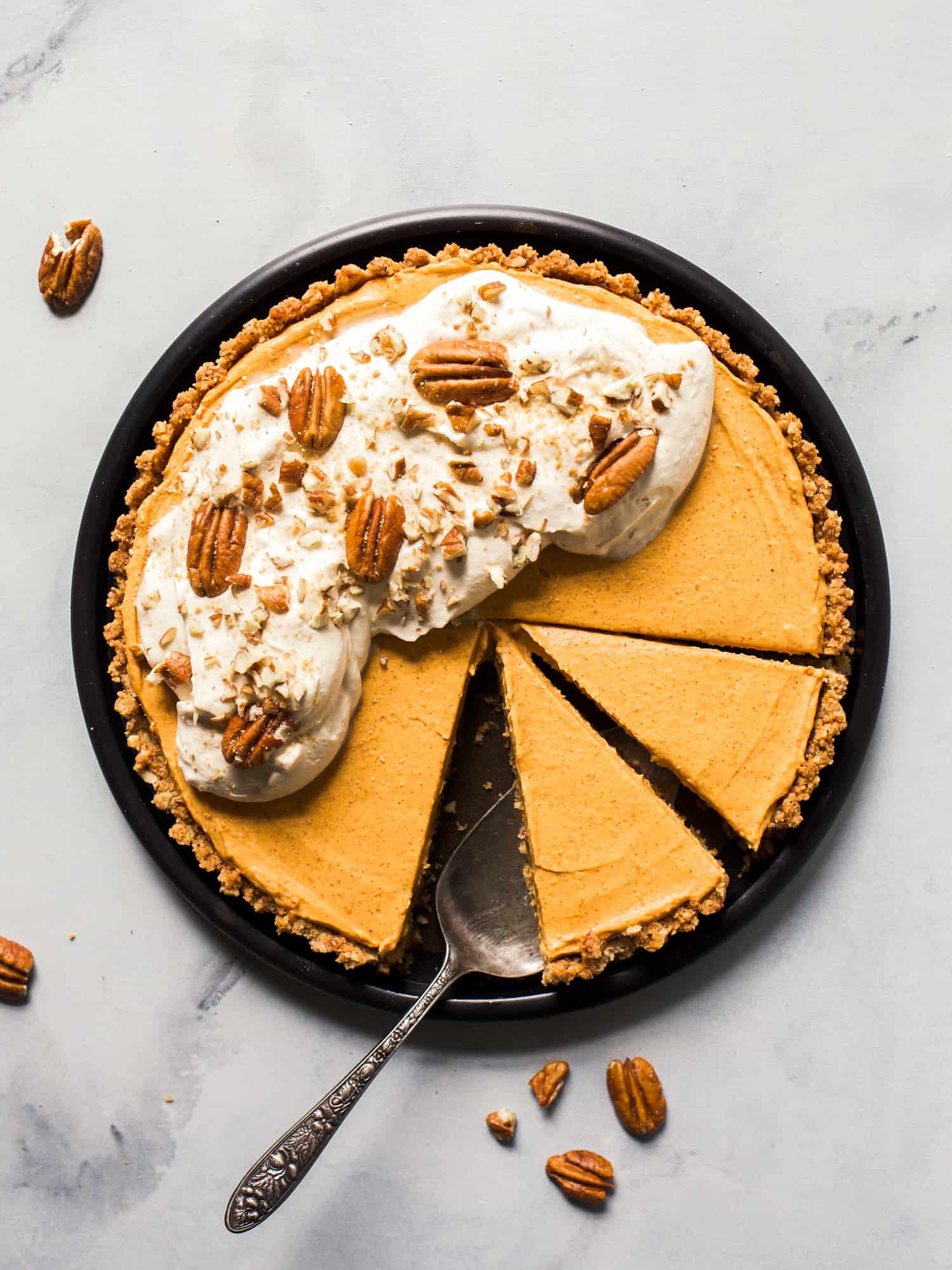 Pumpkin Pecan Tart with Maple Whipped Cream by Wood and Spoon. This is a graham cracker and pecan salted crust baked and filled with a no bake pumpkin cream cheese filling. Flavored with brown sugar and cinnamon, this pie is cool but totally fall. Top the whole thing off with toasty pecans and maple whipped cream. Give this autumn dessert a try for Thanksgiving or upcoming dinner parties! Recipe by Kate wood on thewoodandspoon.com