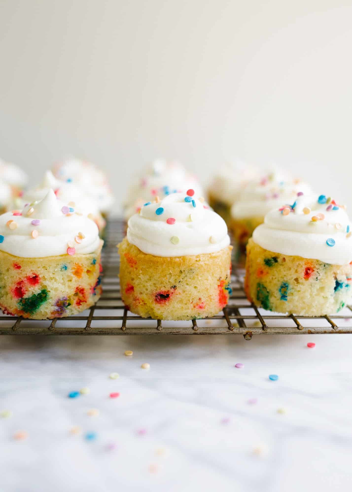 Funfetti Mini Cakes by Wood and Spoon. These are two bite sprinkle cakes, almost like mini cupcakes, made in a mini cheesecake pan. The topping is a light and fluffy whipped cream frosting and the cake taste of nostalgic box birthday cake mix flavor! Learn more about how to make this recipe on thewoodandspoon.com