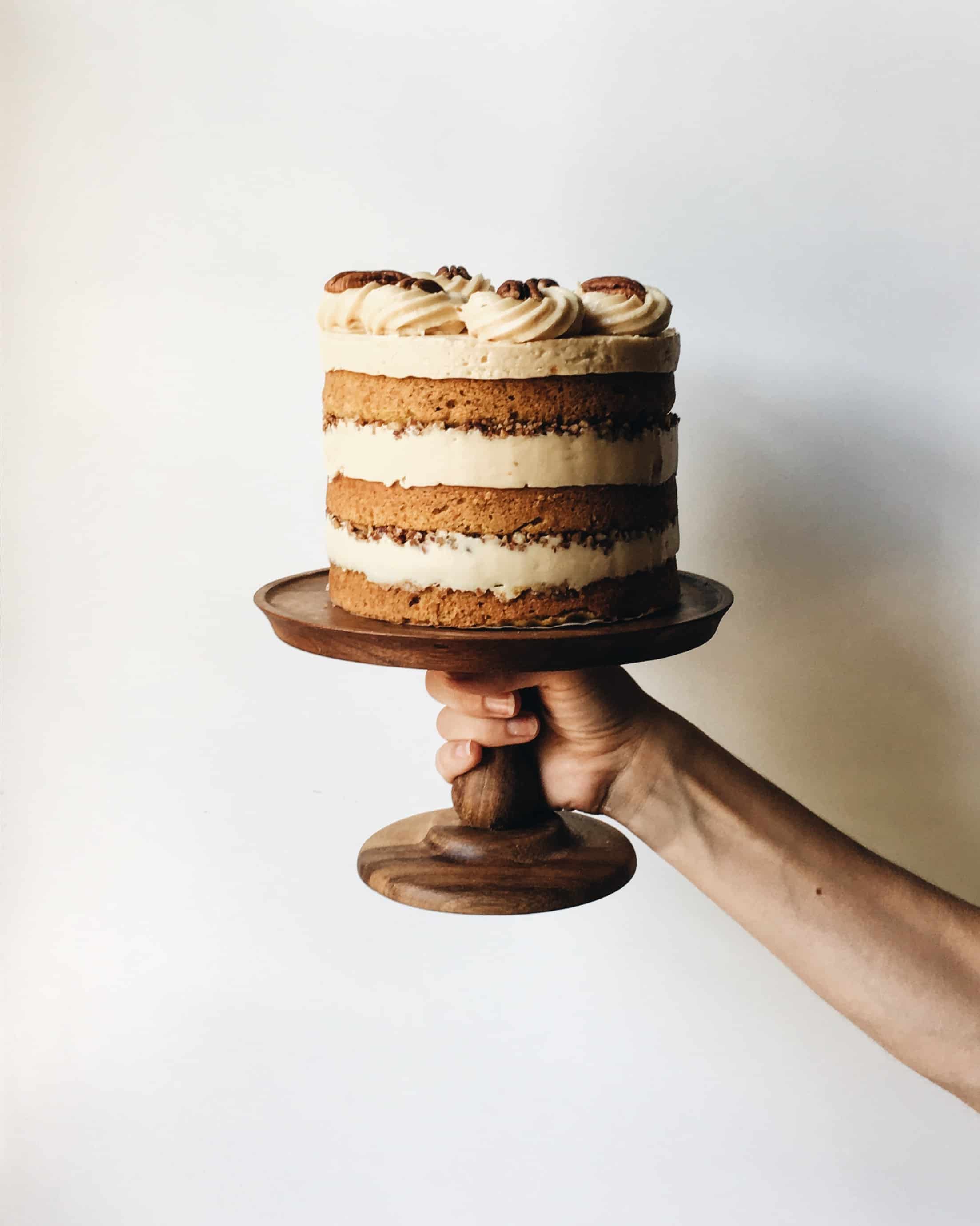 Pumpkin Pecan Cake with Burnt Sugar Frosting Recipe by The Wood and Spoon Blog by Kate Wood. This is a naked pumpkin layer cake with moist, fluffy layers make with cinnamon and pumpkin puree. The cake is filled with a sweet and salty pecan filling. The frosting is a southern style, almost caramel flavored frosting make by caramelizing sugar until it is almost burnt. The whole thing is layered together for an impressive layer cake that takes like fall. It is a great birthday , celebration, thanksgiving. Make this show stopper for your next event. Thewoodandspoon.com