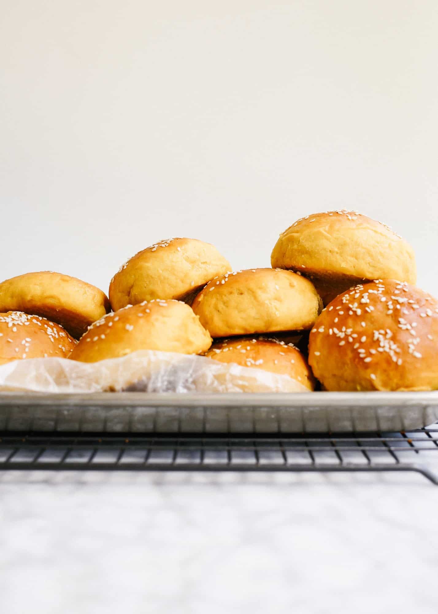 Sweet Potato Buns by Wood and Spoon blog. These are fluffy potato hamburger buns using mashed sweet potato. They are thick and tender and would be terrific with burgers, barbecue, or Thanksgiving leftover sandwiches! Find out how to make this simple homemade yeast bread rolls on thewoodandspoon.com