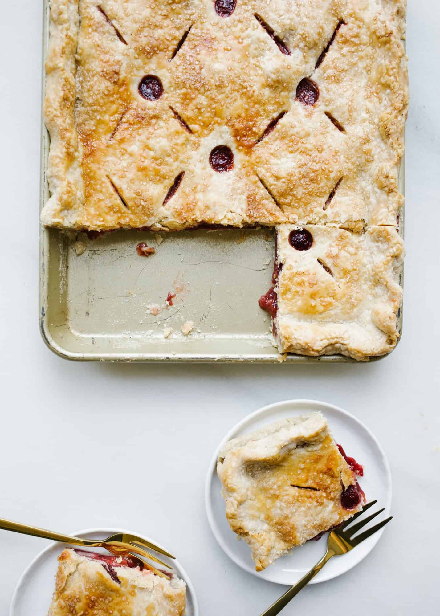 Strawberry Slab Pie by Wood and Spoon. This is a make-ahead feed-a-crowd kind of recipe featuring fresh summer fruit, vanilla, and loads of flaky butter pie crust. This pie ends up being berry pie bars that are easy to serve large groups and almost require no plate or fork. Learn how to make large batch pie with simple homemade filling on thewoodandspoon.com by Kate Wood.