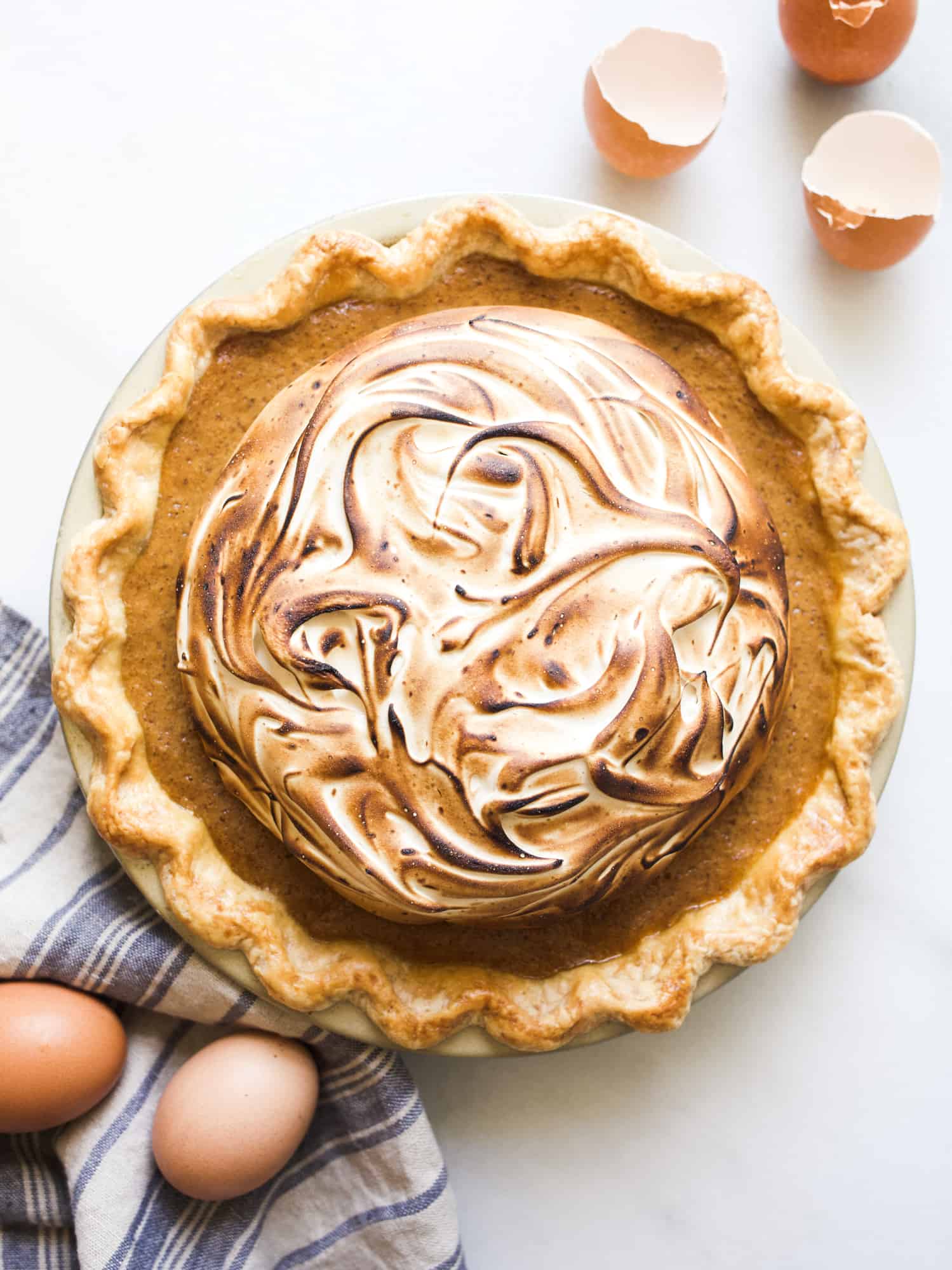 Sweet Potato Meringue Pie by Wood and Spoon blog. This is a butter and shortening pie crust blind baked and filled with a sweet potato, pumpkin tasting filling, cinnamon, and warm spices. The topping is a brown sugar and cinnamon marshmallow meringue that is cooked on the stove and whipped to stiff peaks. The whole thing is torched for a toasty golden finish. Read more about this fall autumn favorite pie for holidays (especially thanksgiving!) on thewoodandspoon.com by Kate Wood