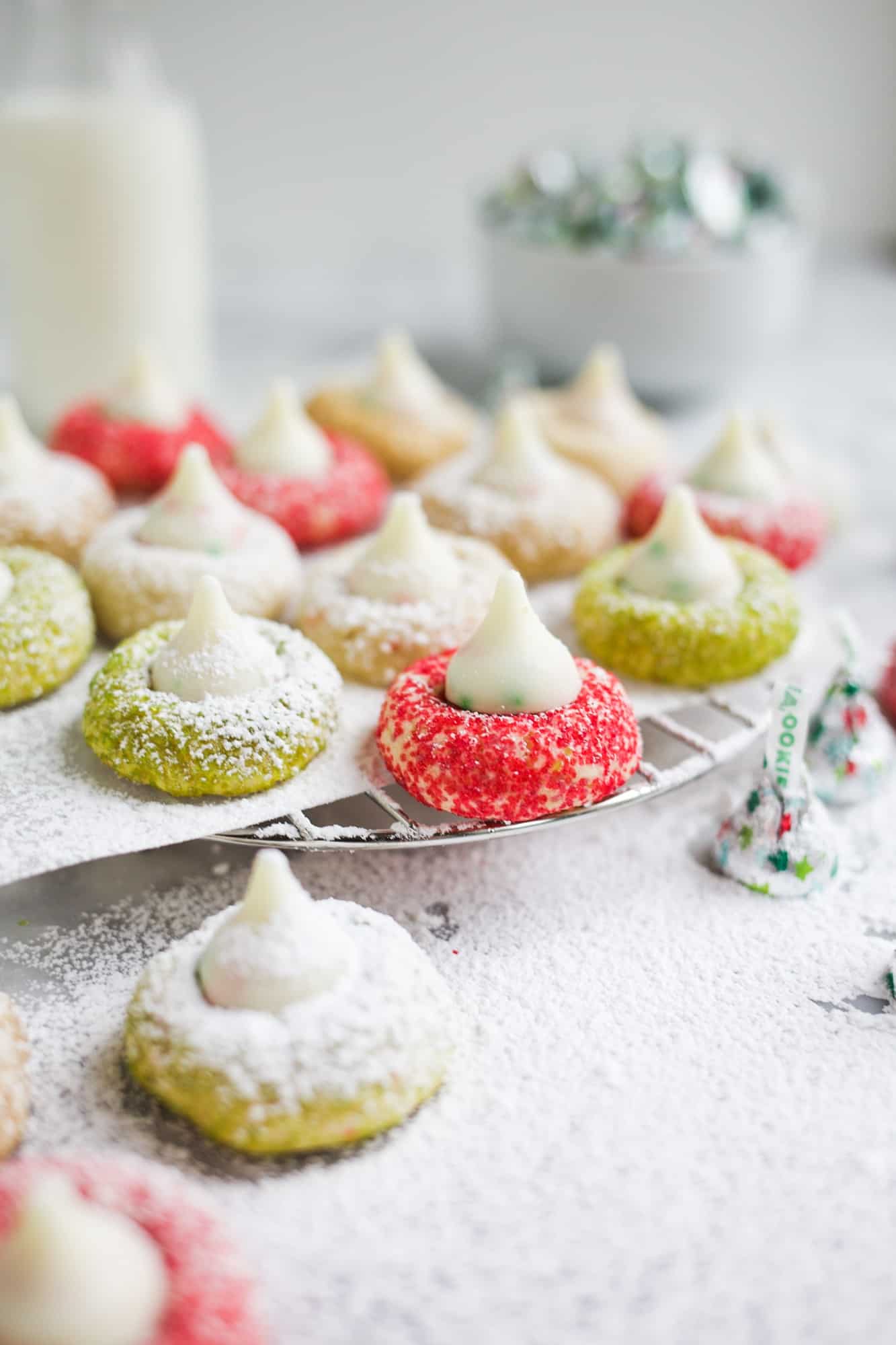 Holiday Sugar Cookie Blossoms by Wood and Spoon. These are Hershey Kisses cookies made with sugar cookie dough, sanding sugar, and sugar cookie candies KISSES. This is a simple recipes that even kids will love to help out with and they're perfect for Christmas and holidays. Learn more about the recipe on thewoodandspoon.com