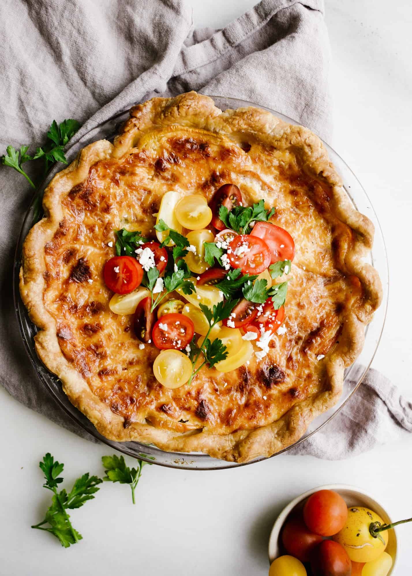 Tomato Pie by Wood and Spoon. This is a simple summer pie of fresh farm tomatoes, cheddar cheese, Italian herbs, and a buttery flaky crust! Learn how simple it is to make this savory pie that makes for a terrific lunch or dinner option! Serve this pie for summer gatherings! Learn more on thewoodandspoon.com