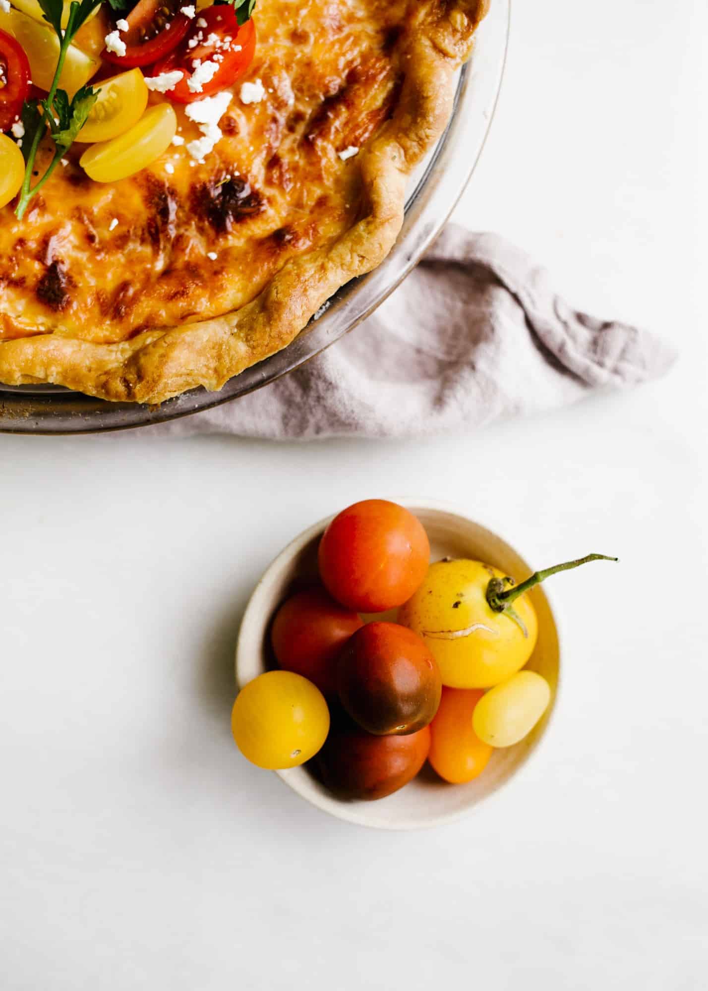 Tomato Pie by Wood and Spoon. This is a simple summer pie of fresh farm tomatoes, cheddar cheese, Italian herbs, and a buttery flaky crust! Learn how simple it is to make this savory pie that makes for a terrific lunch or dinner option! Serve this pie for summer gatherings! Learn more on thewoodandspoon.com