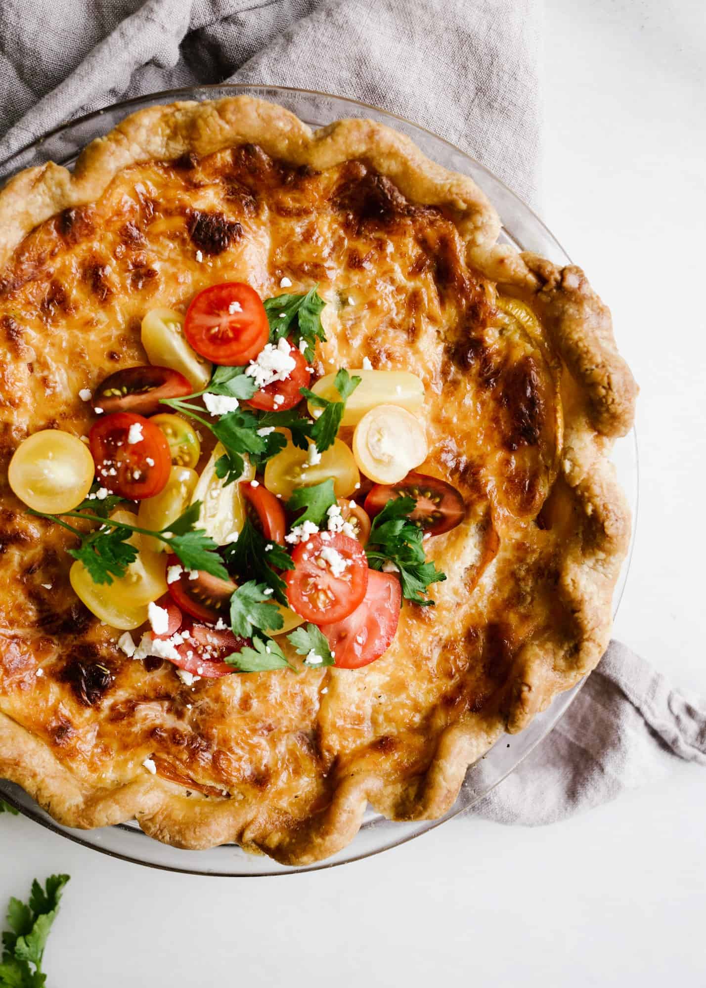 Tomato Pie by Wood and Spoon. This is a simple summer pie of fresh farm tomatoes, cheddar cheese, Italian herbs, and a buttery flaky crust! Learn how simple it is to make this savory pie that makes for a terrific lunch or dinner option! Serve this pie for summer gatherings! Learn more on thewoodandspoon.com