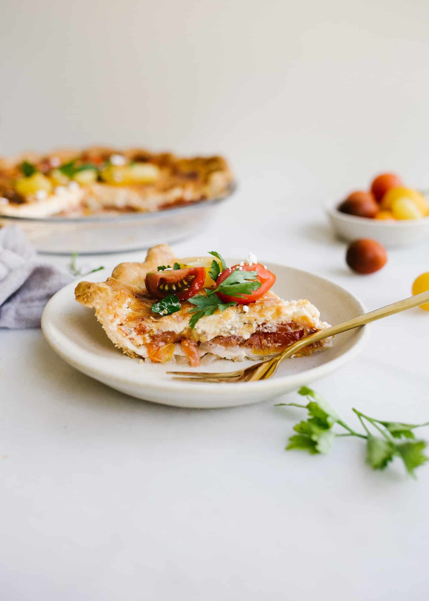 Tomato Pie by Wood and Spoon. This is a simple summer pie of fresh farm tomatoes, cheddar cheese, Italian herbs, and a buttery flaky crust! Learn how simple it is to make this savory pie that makes for a terrific lunch or dinner option! Serve this pie for summer gatherings! Learn more on thewoodandspoon.com