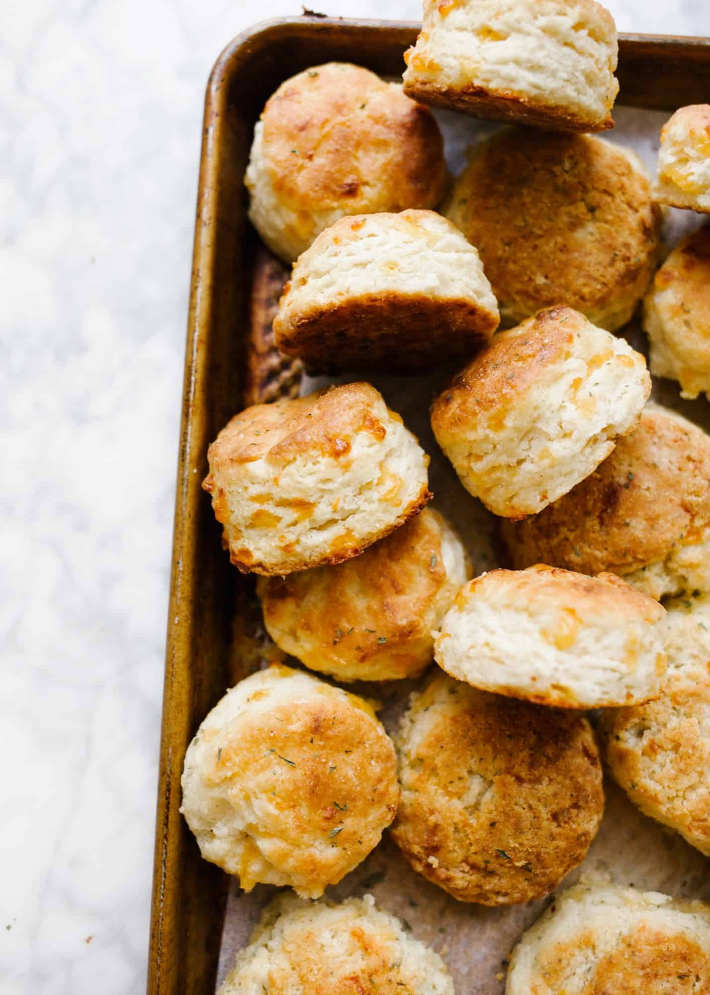 Cheddar Cornmeal Biscuits by Wood and Spoon blog. These are layered, buttery, Southern-style biscuits flavored with cheddar cheese, herbs, and cornmeal! The texture comes out to somewhere between cornbread, muffins, and biscuits! These baked breads are loaded with flavor and serve as a great side item or bread option for dinners all year round. Give these flaky breakfast treats a try on thewoodandspoon.com