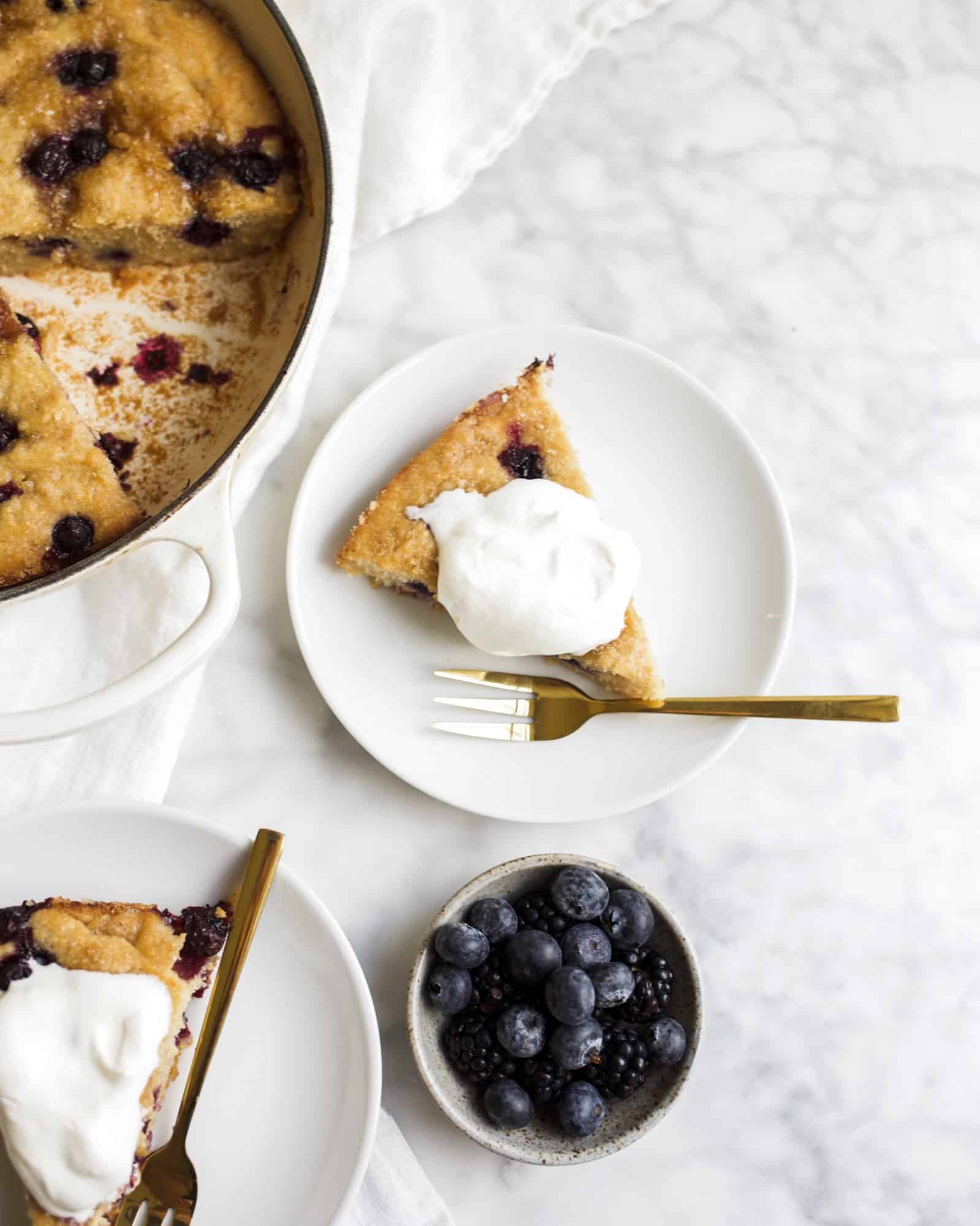 Blueberry Cornbread Recipe by The Wood and Spoon Blog by Kate Wood. This is a cornmeal and flour skillet cake made with fresh blueberries and sugar. A simple, one bowl cake recipe made in a cast iron skillet, speckled with summer berries and sprinkled with powdered sugar. You can serve this with honey butter or whipped cream as dessert, or eat thick slices of it for breakfast. Find the recipe at thewoodandspoon.com