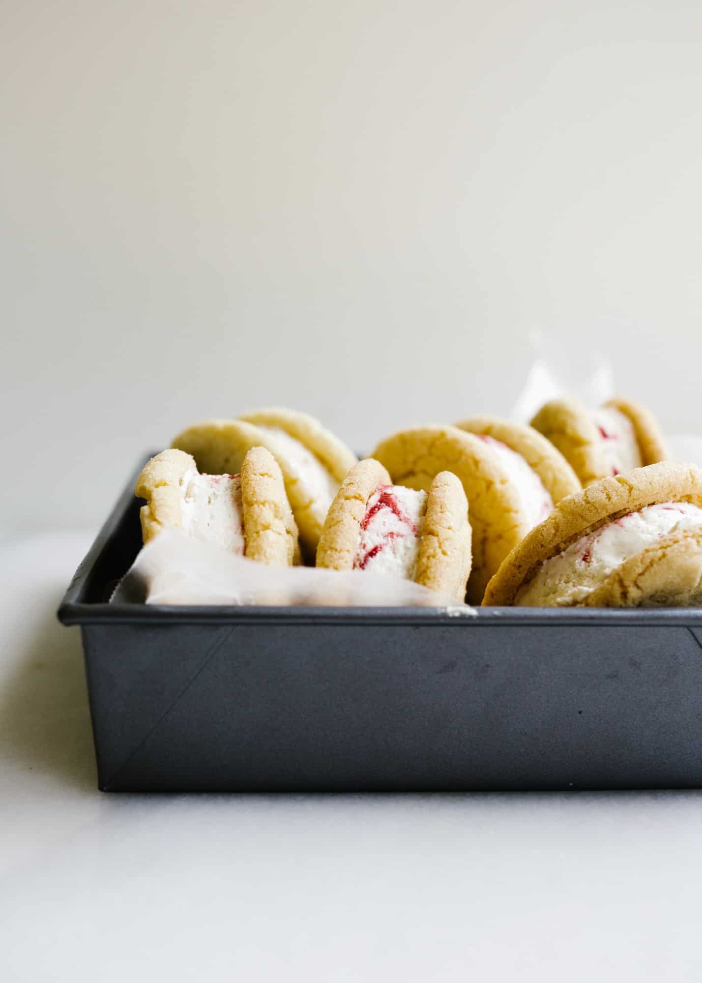 Sugar Cookie Ice Cream Sandwiches with Raspberry Ripple Ice Cream by Wood and Spoon blog. This is Sarah Keiffer's recipe for chewy sugar cookies loaded with no-sugar raspberry swirl ice cream. The ice cream is simple to put together and requires no ice cream machine. These are delicious frozen desserts! Makes enough jumbo treats to share with a crowd and is perfect for summer days! Find the recipe on thewoodandspoon.com