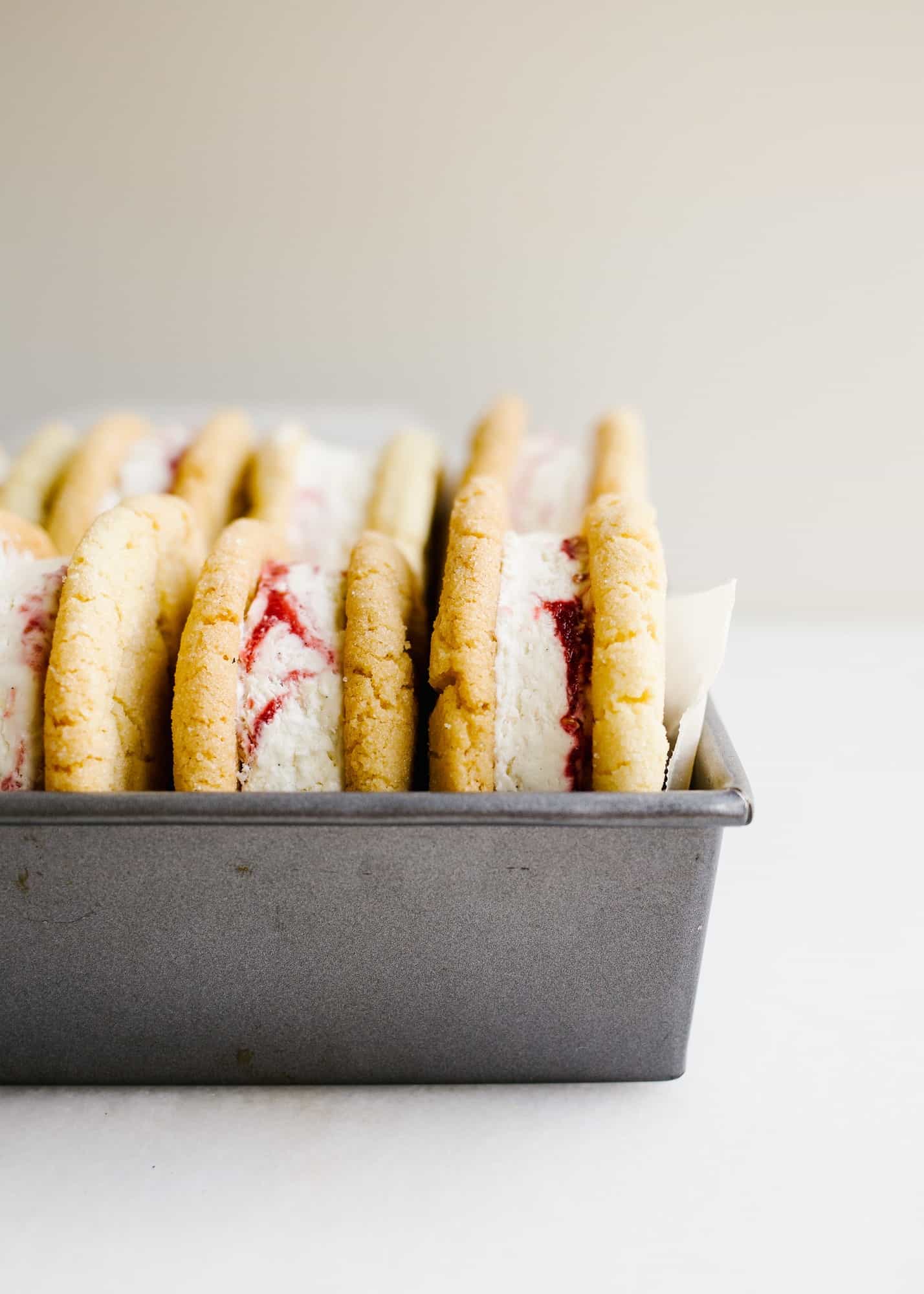 Sugar Cookie Ice Cream Sandwiches with Raspberry Ripple Ice Cream by Wood and Spoon blog. This is Sarah Keiffer's recipe for chewy sugar cookies loaded with no-sugar raspberry swirl ice cream. The ice cream is simple to put together and requires no ice cream machine. These are delicious frozen desserts! Makes enough jumbo treats to share with a crowd and is perfect for summer days! Find the recipe on thewoodandspoon.com